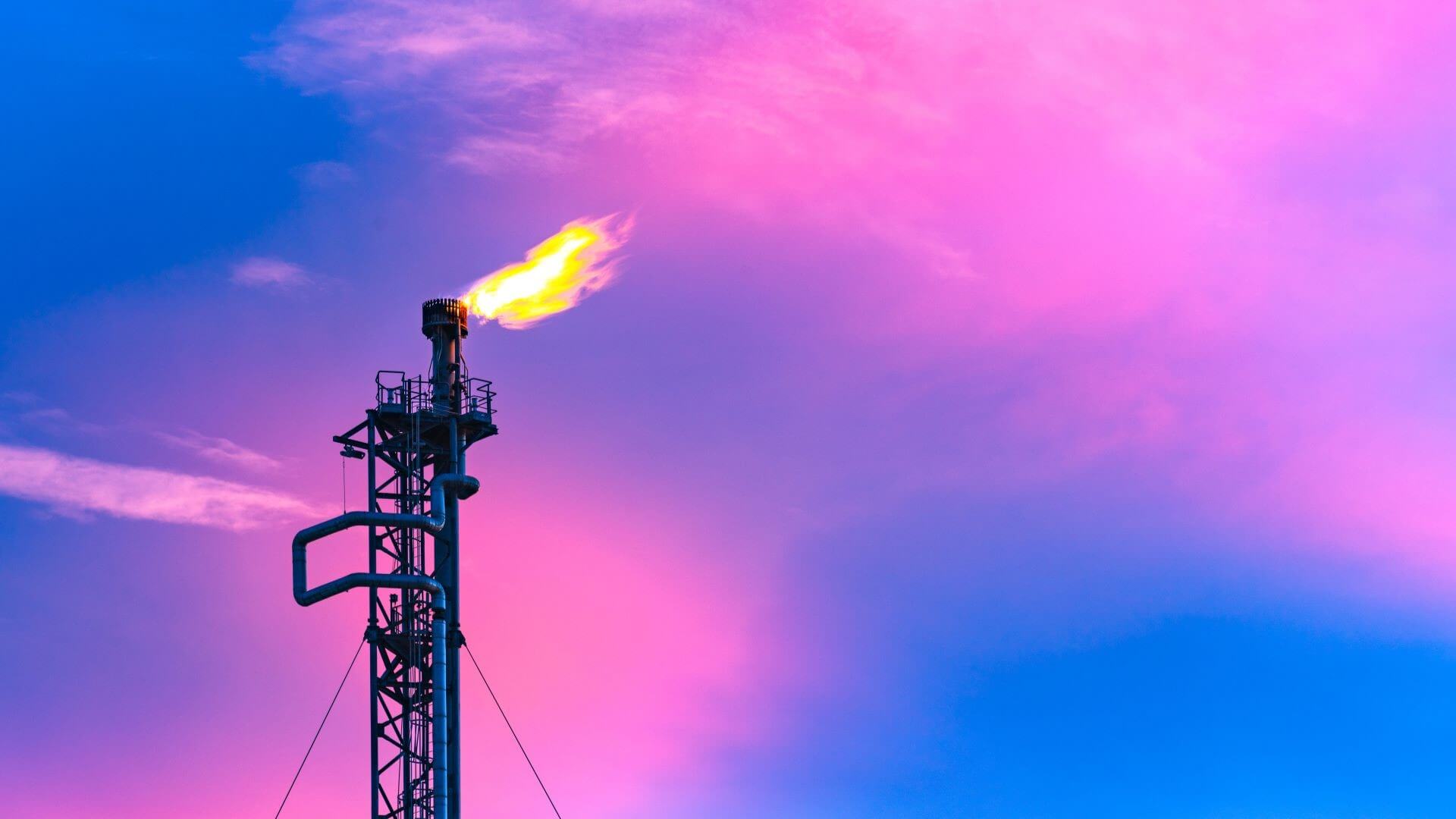 Close up of gas flare set against dramatic blue and pink sky