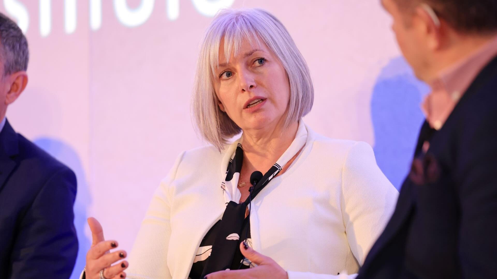 Louise Kingham sitting on stage, talking, between two other panel members