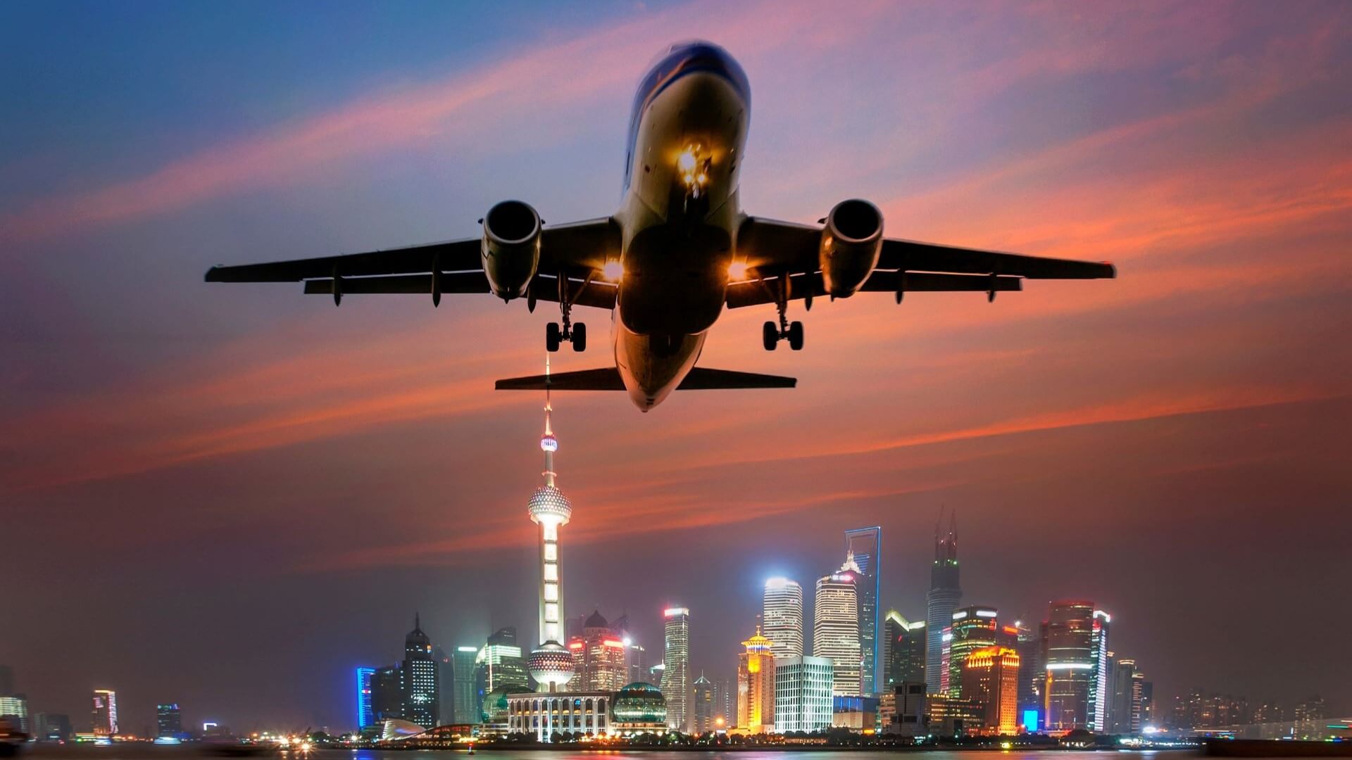 Aircraft taking off over Shanghai skyline at night