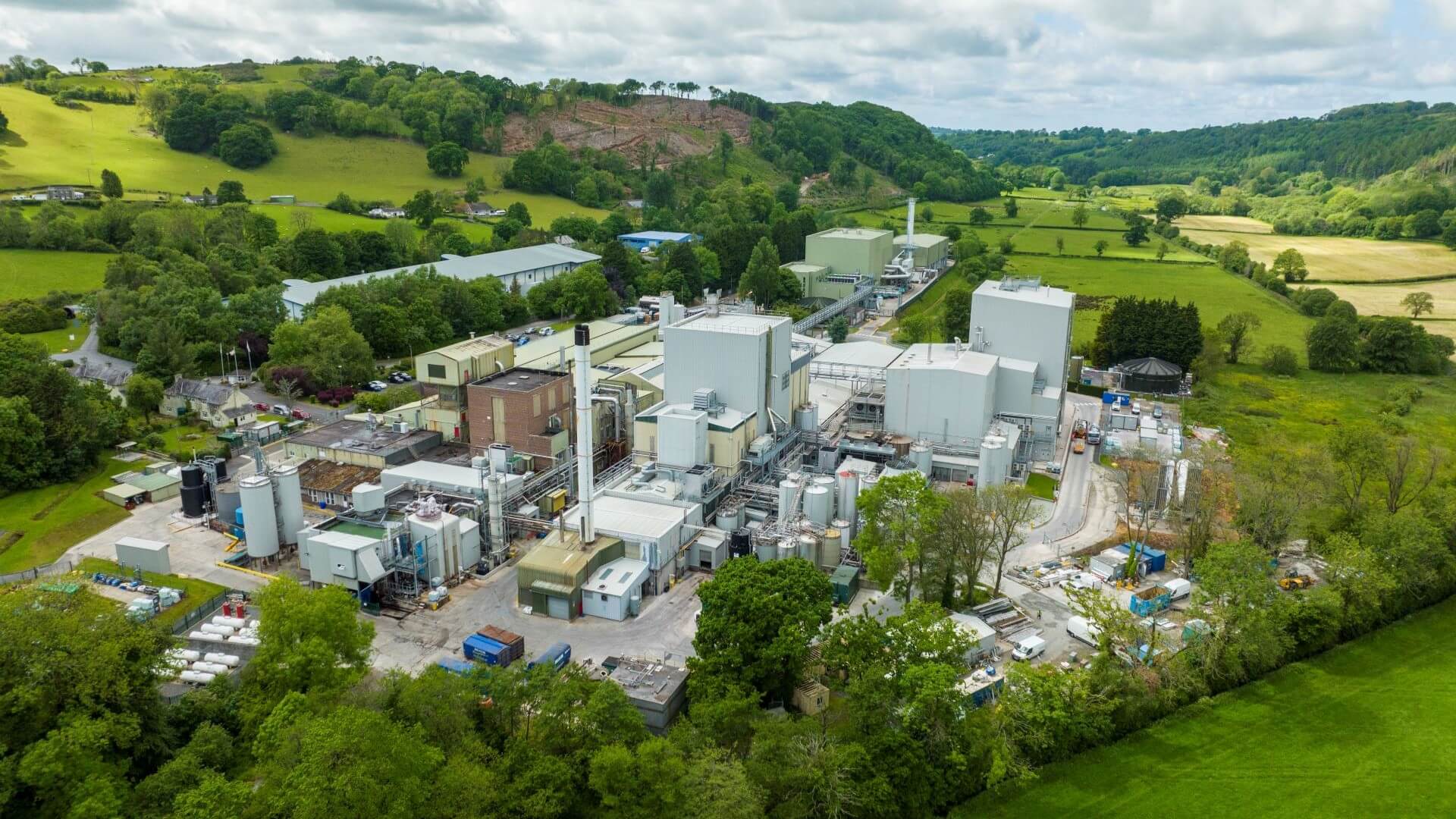 Aerial overview of dairy plant facilities set among green hills in Wales