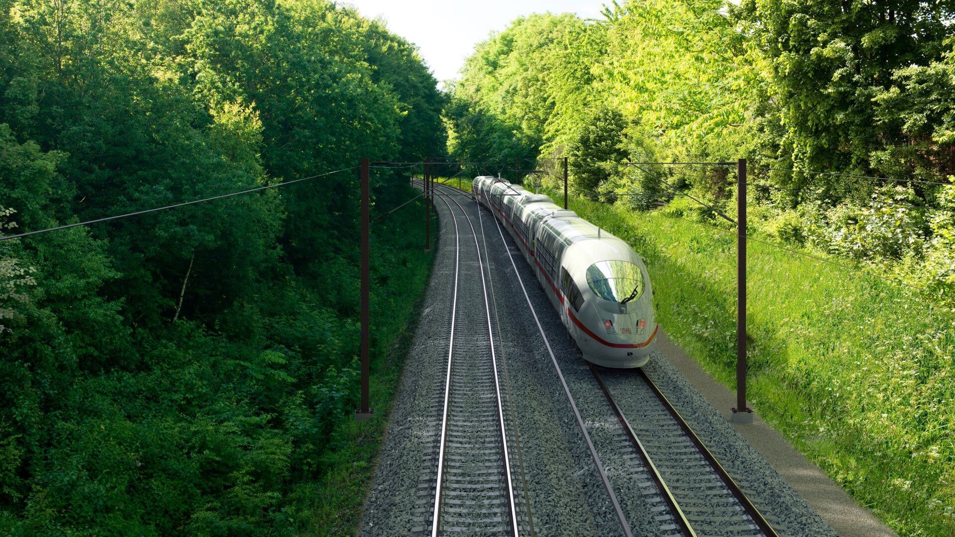Sleek silver coloured train on tracks with green trees either side