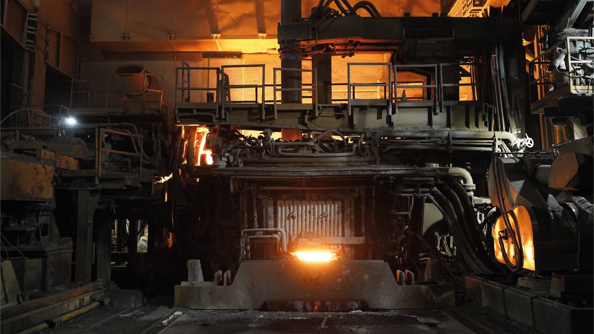 Furnace with bright orange fire against dark background of industrial plant