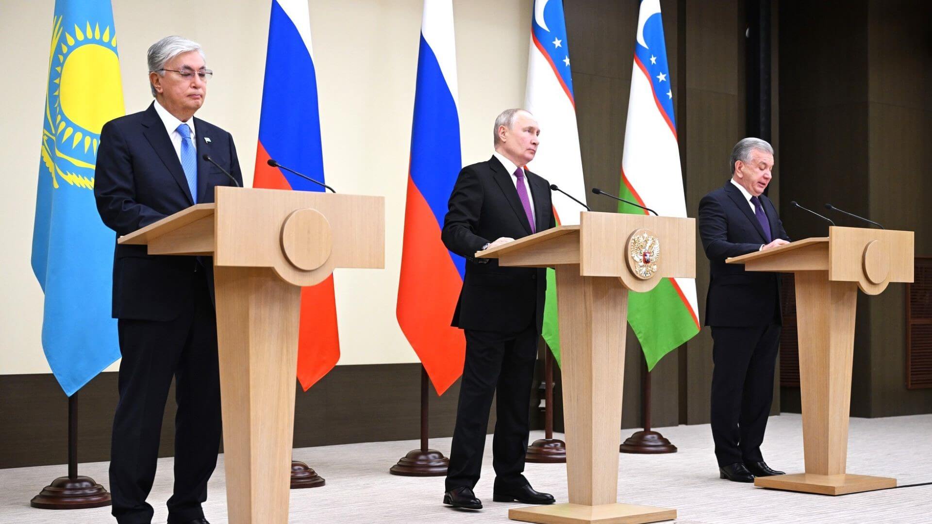 Kazakh, Russian and Uzbek Presidents standing behind lecturns on stage at a press conference, with national flags behind them