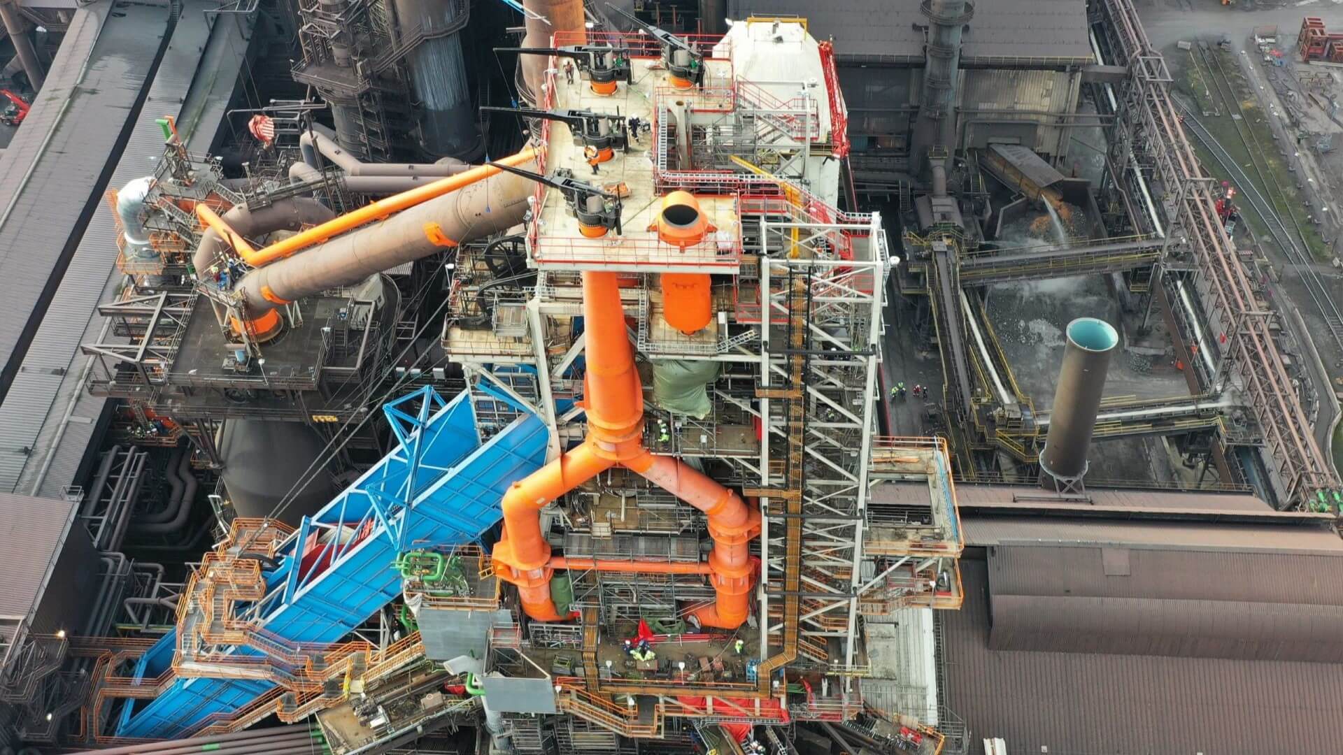 Aerial view over exterior of industrial building covered with metal pipework and equipement