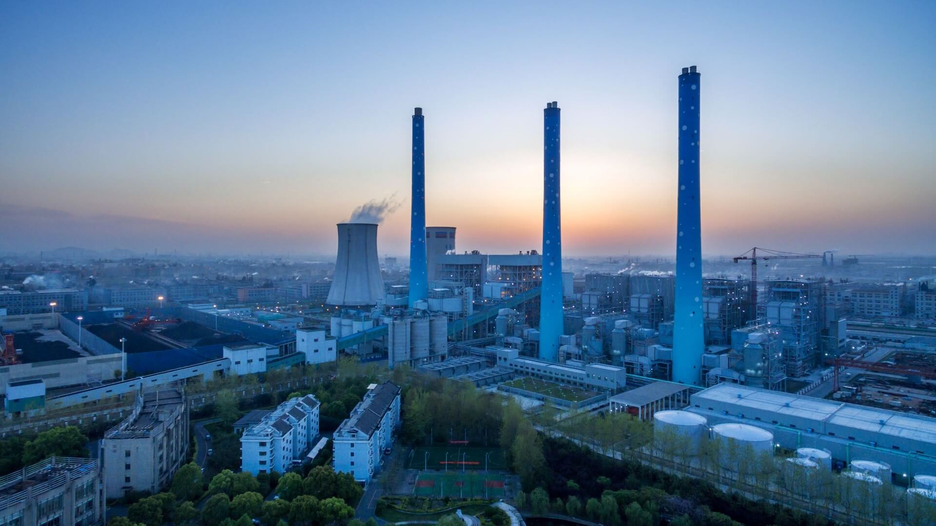 Aerial overview of coal-fired plant with chimney stacks set against a twilight sky