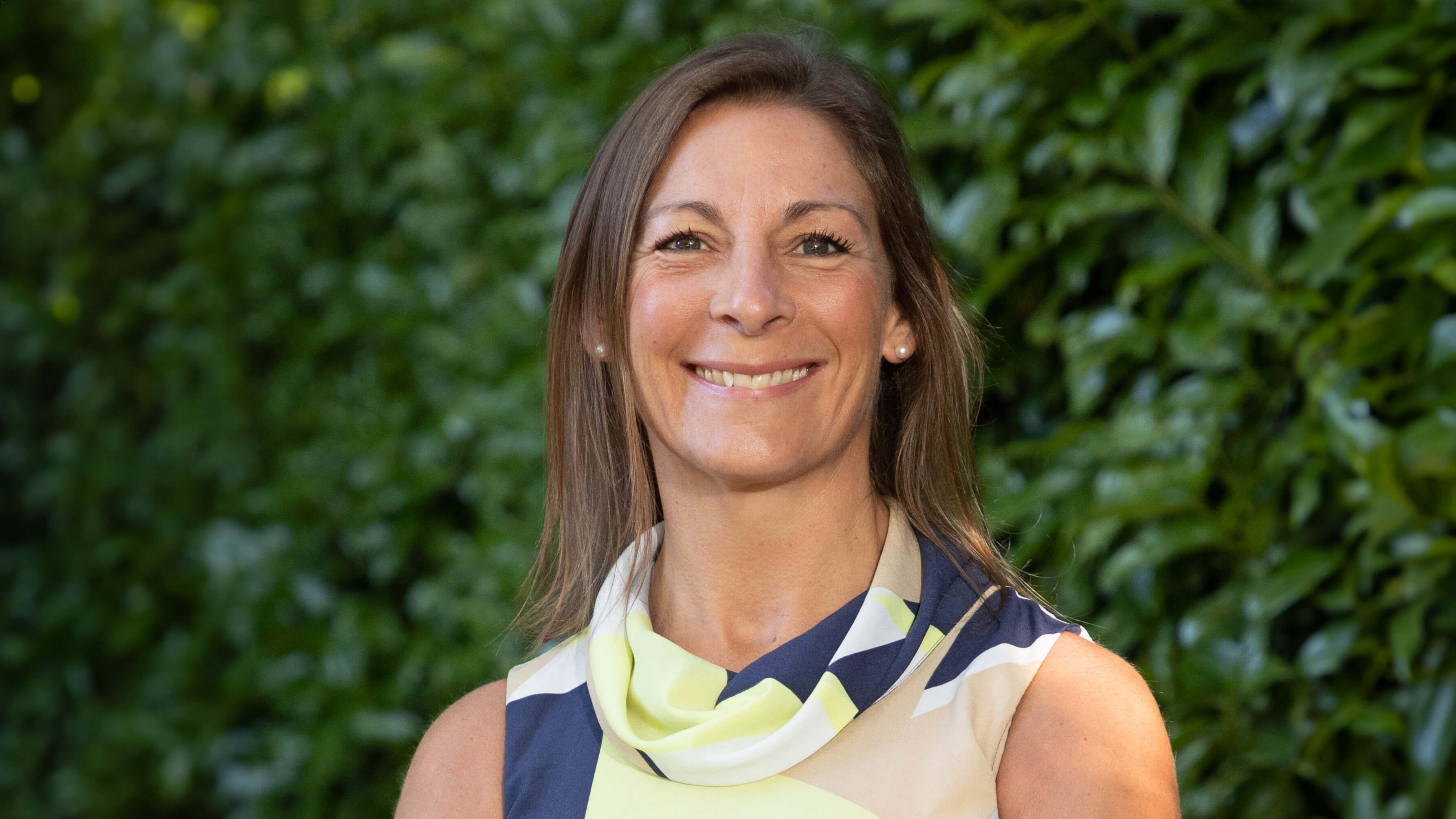 Head and shoulders photo of Kate Gilmartin, with a green leafy hedge in the background