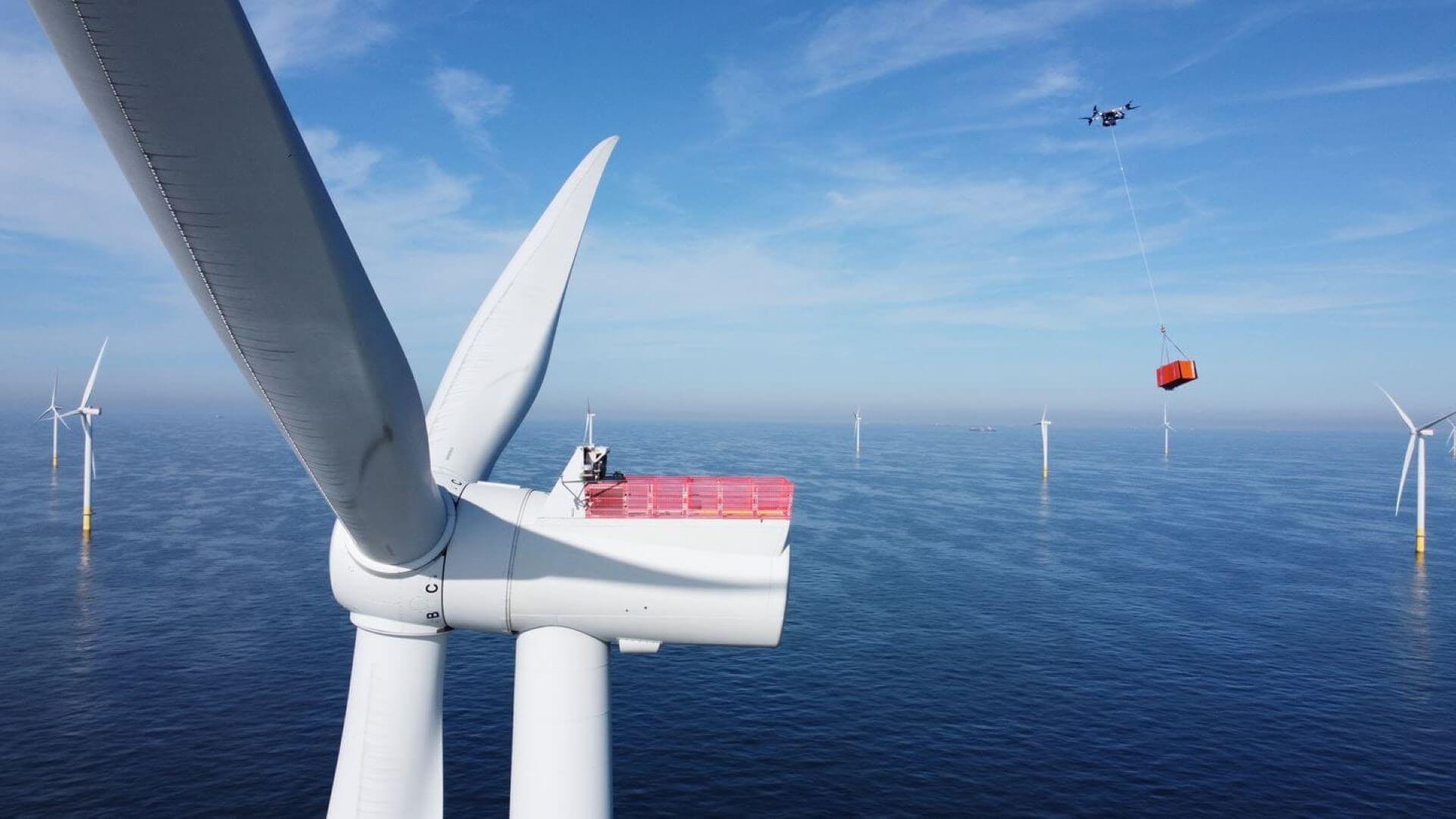 Close up of offshore wind turbine with drone carrying cargo in the background