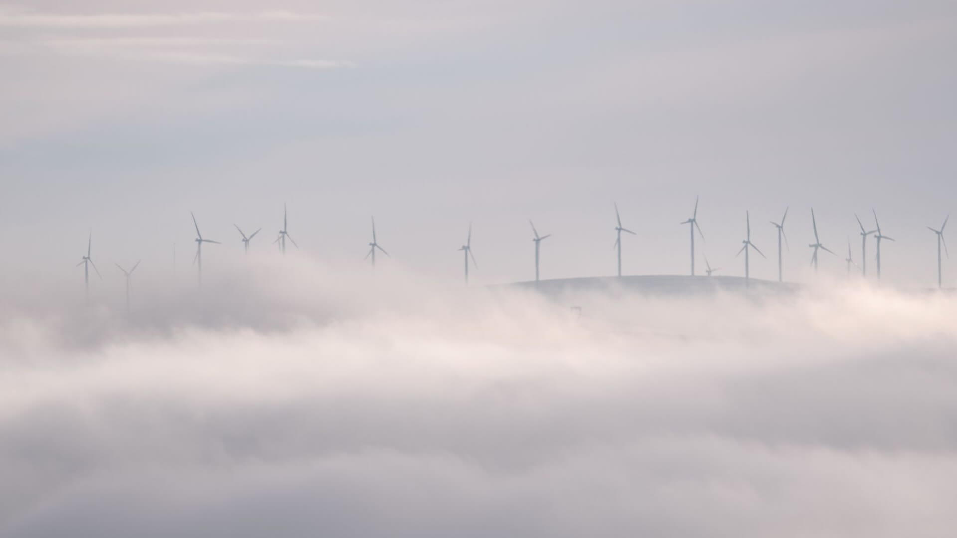 Onshore wind farm on a hill surrounded by clouds