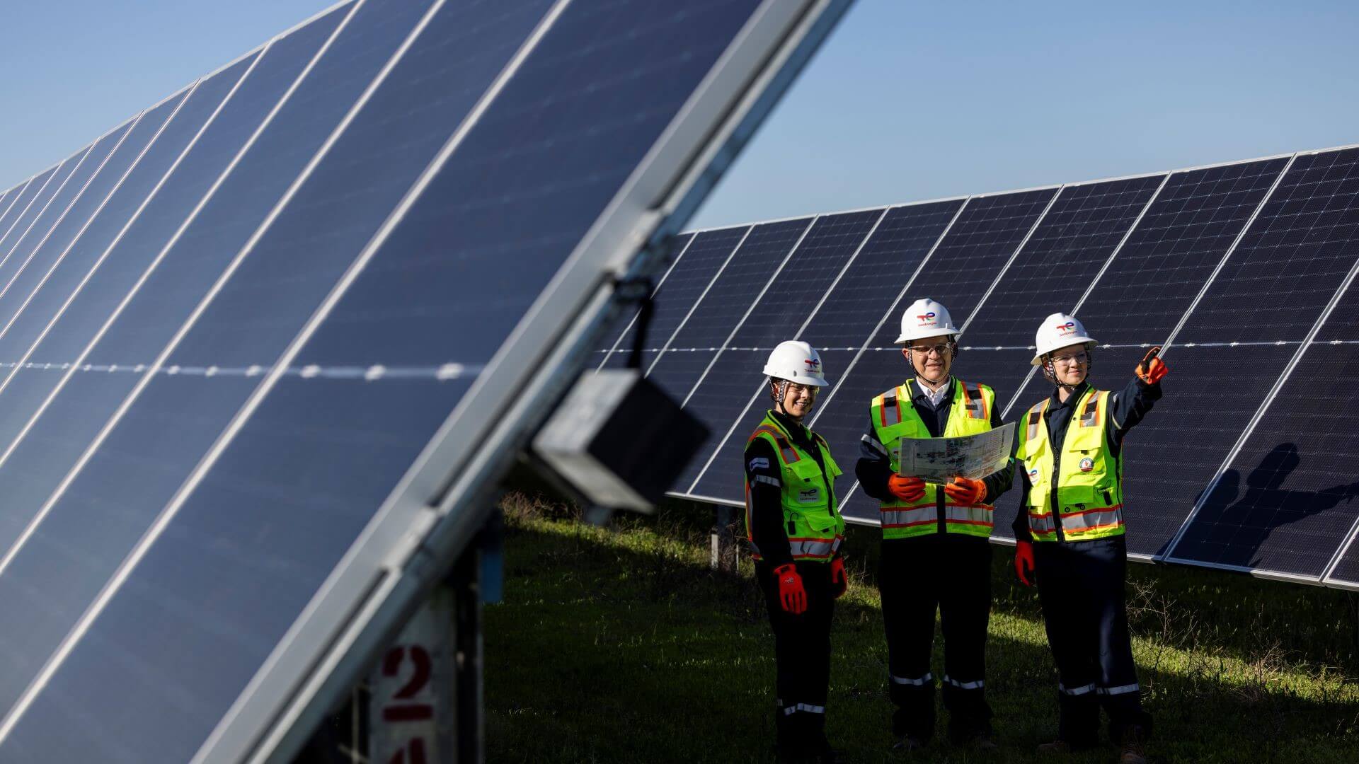 Three engineers in between rows of solar panels at Danish Fields solar farm