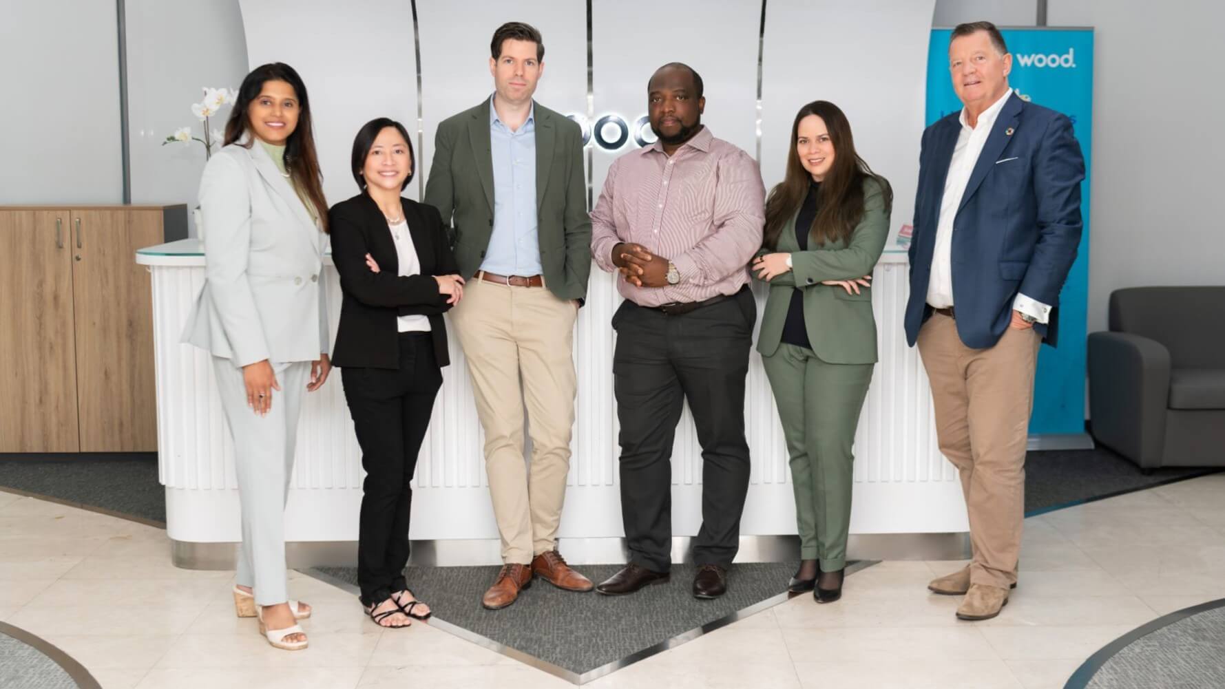 Row of six people standing side by side in building foyer
