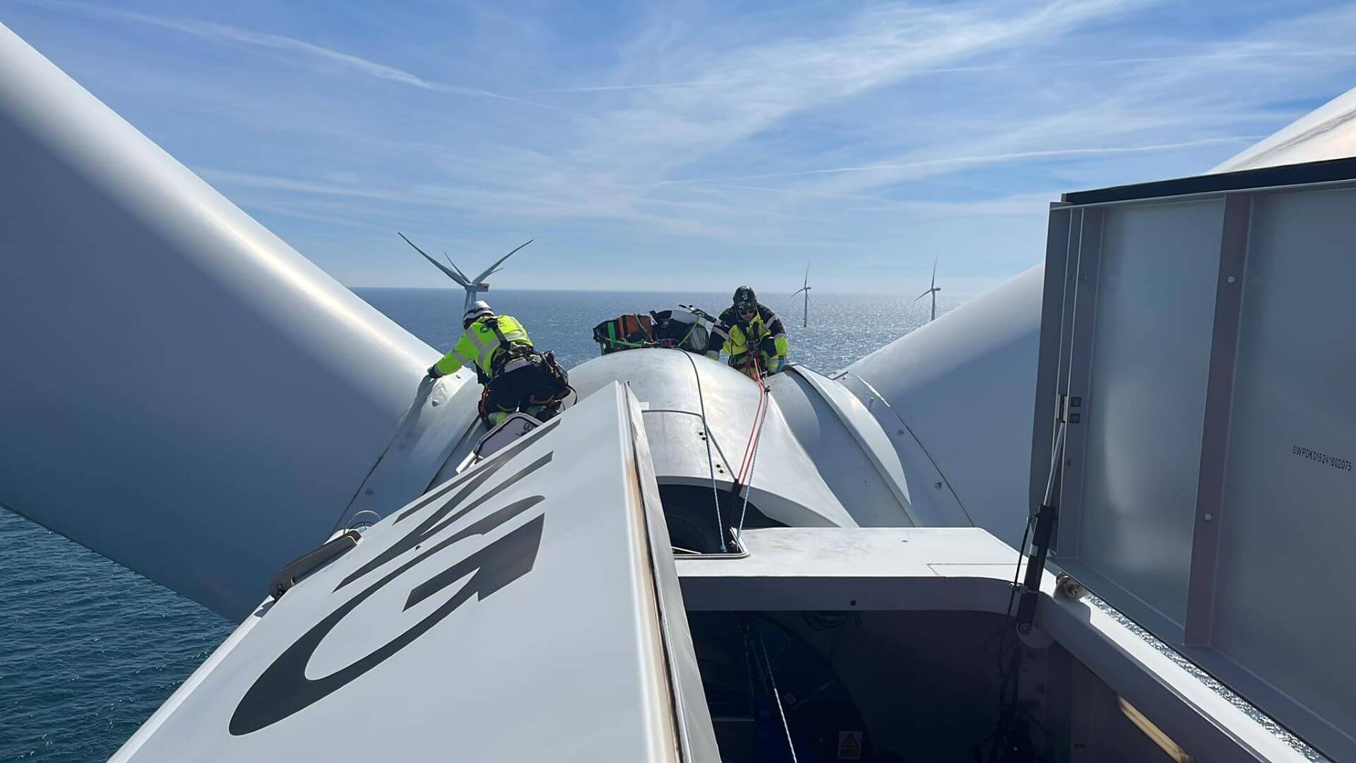 Two engineers working on top of offshore wind turbine