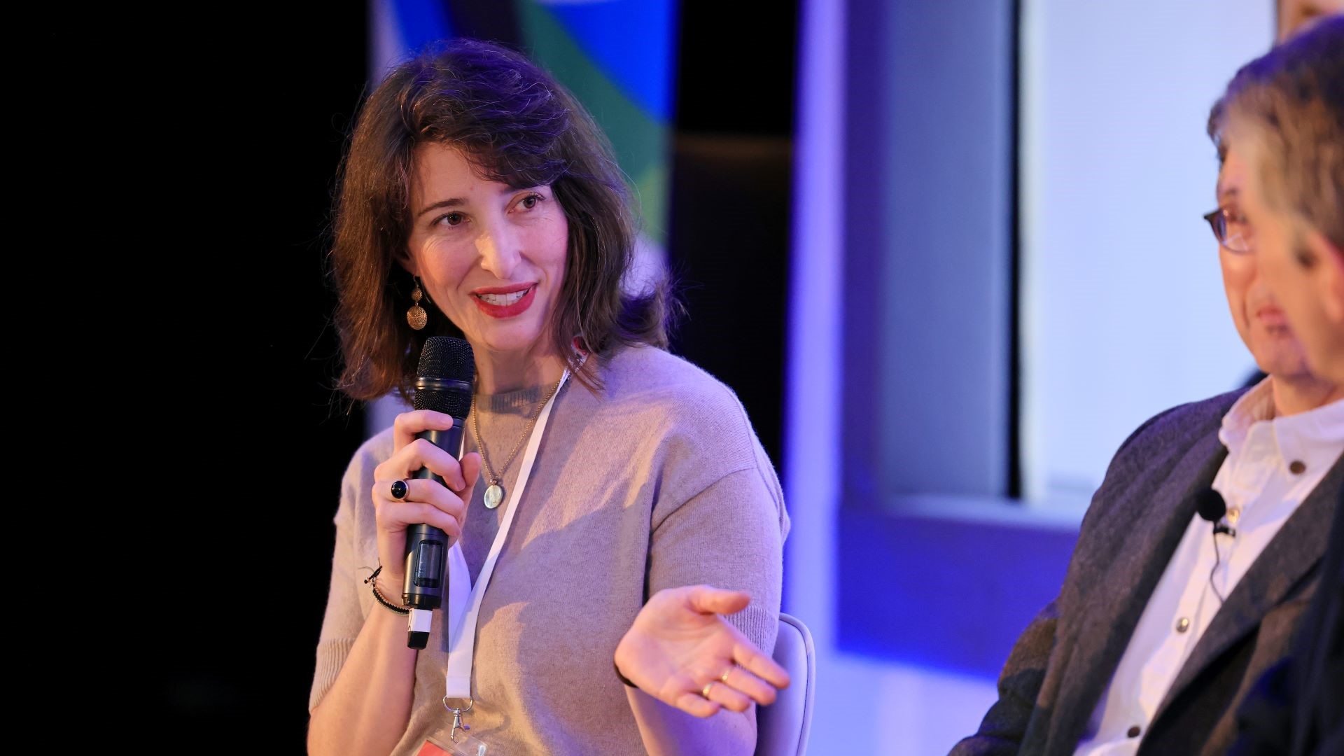 Close up of Dr Jemma Green holding a microphone and speaking to other people on conference panel