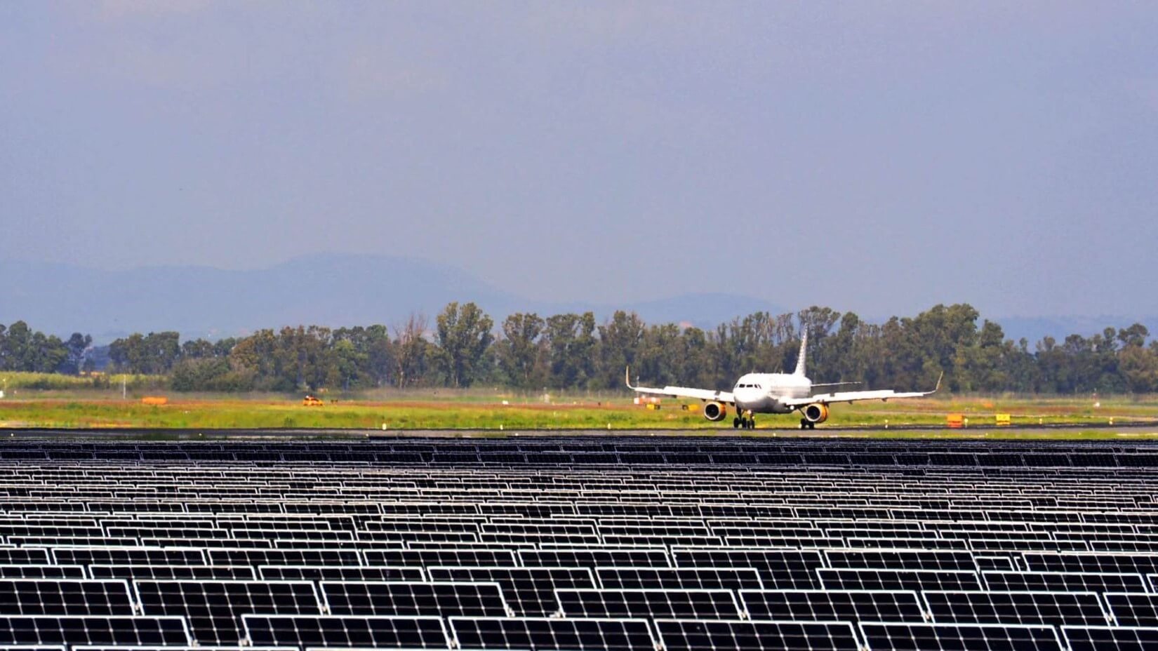 An aeroplane on the runway with solar panels in the foreground