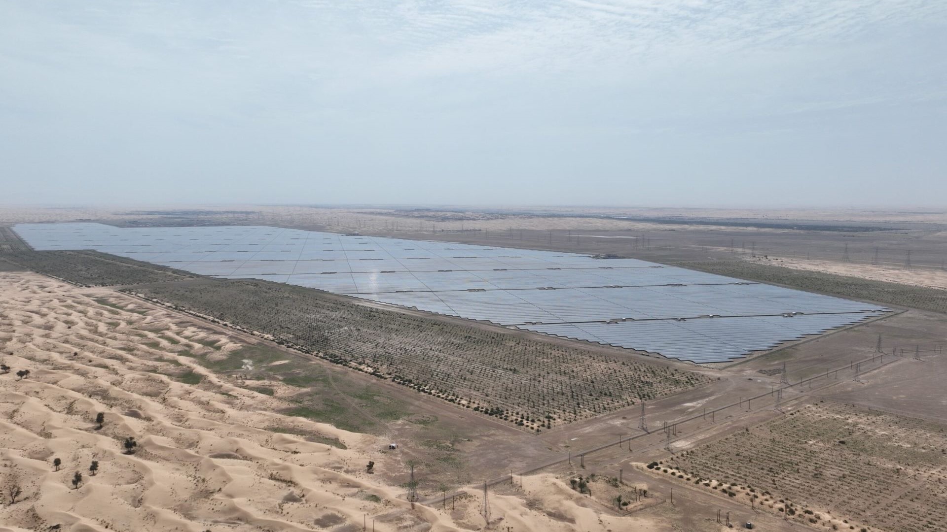 Aerial overiew of solar farm in desert, showing row upon row of solar panels in bright sunlight