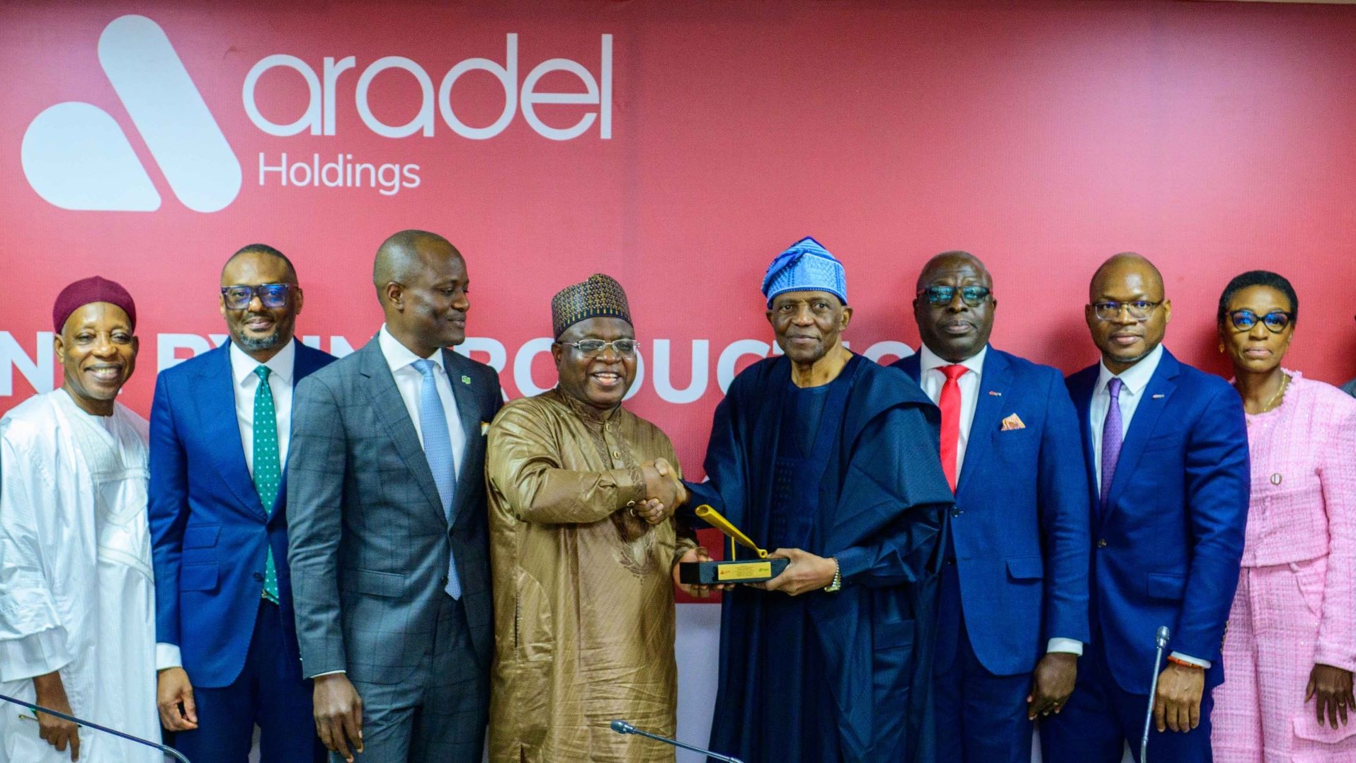 Representatives of Africa company Aradel Holdings, lined up in a row running left to right across photo, with large red screen behind showing Aradel logo in white