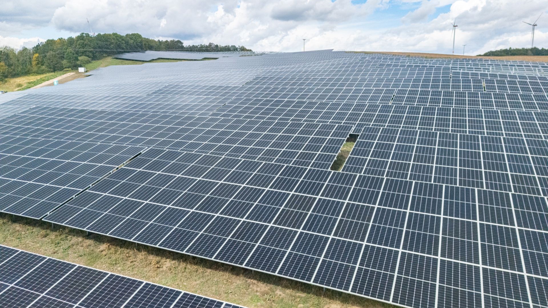 Row upon row of solar panels on grass field extending into the distance