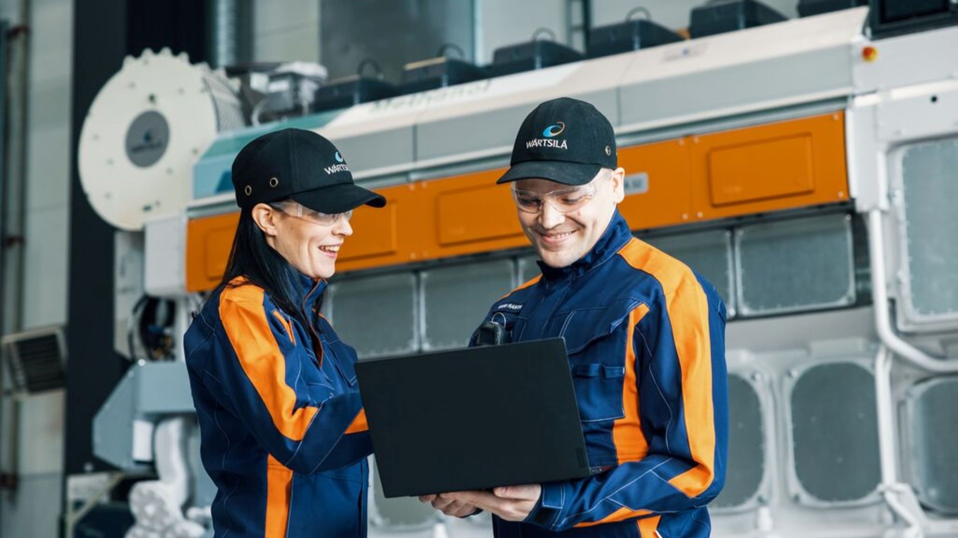 Two Wärtsilä employees in uniform with laptop 