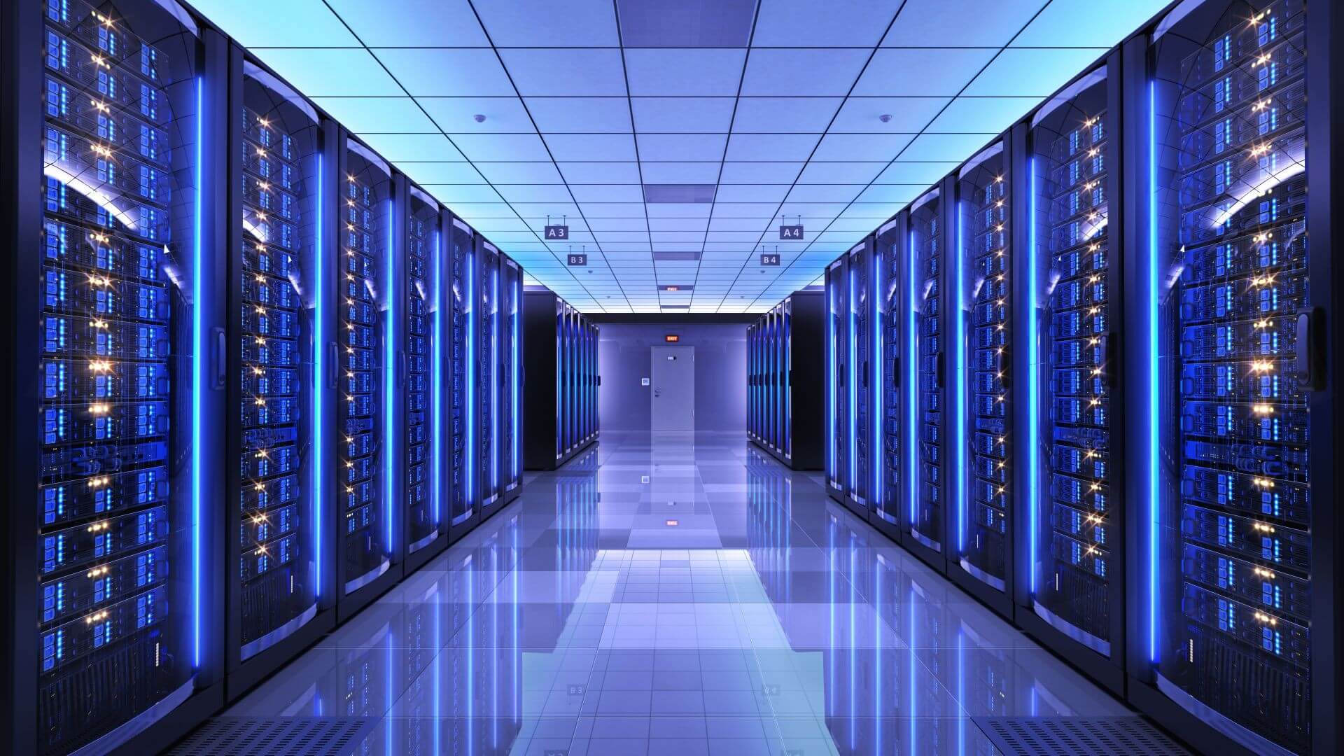 View down two rows of data centre computer racks to left and right of image, lit up with blue lighting