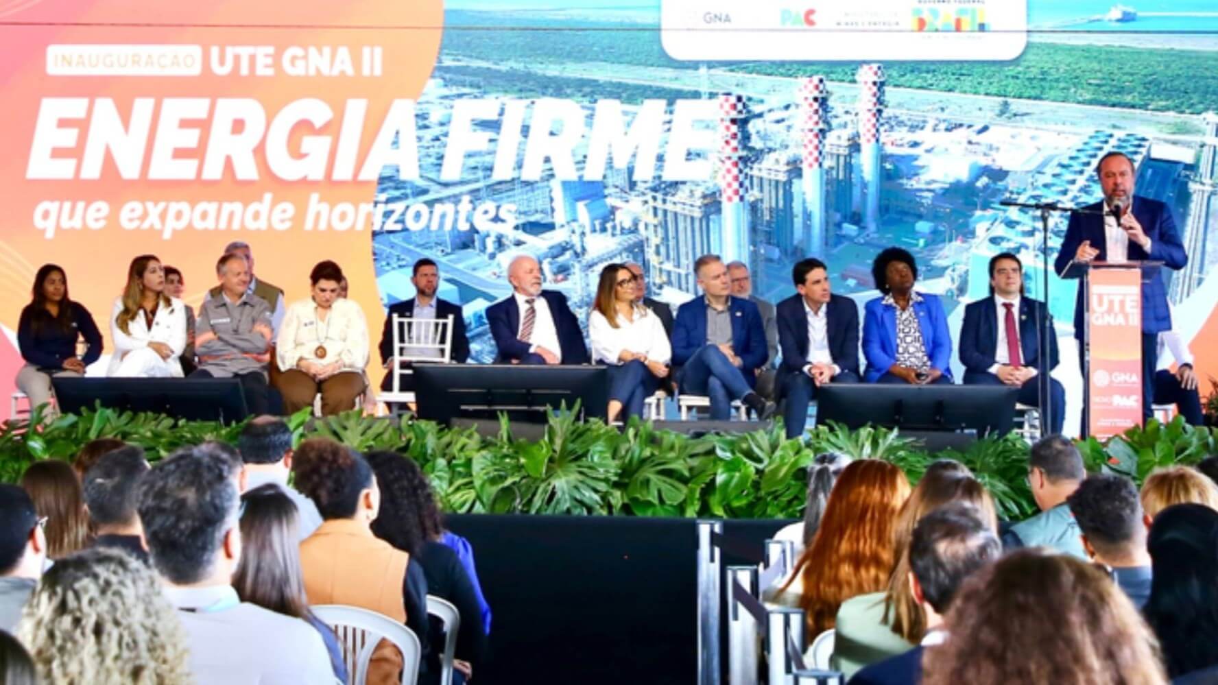 Brazilian President Luiz Inácio Lula da Silva standing at podium, alongside row of men and women on stage, speaking to an audience of people looking on