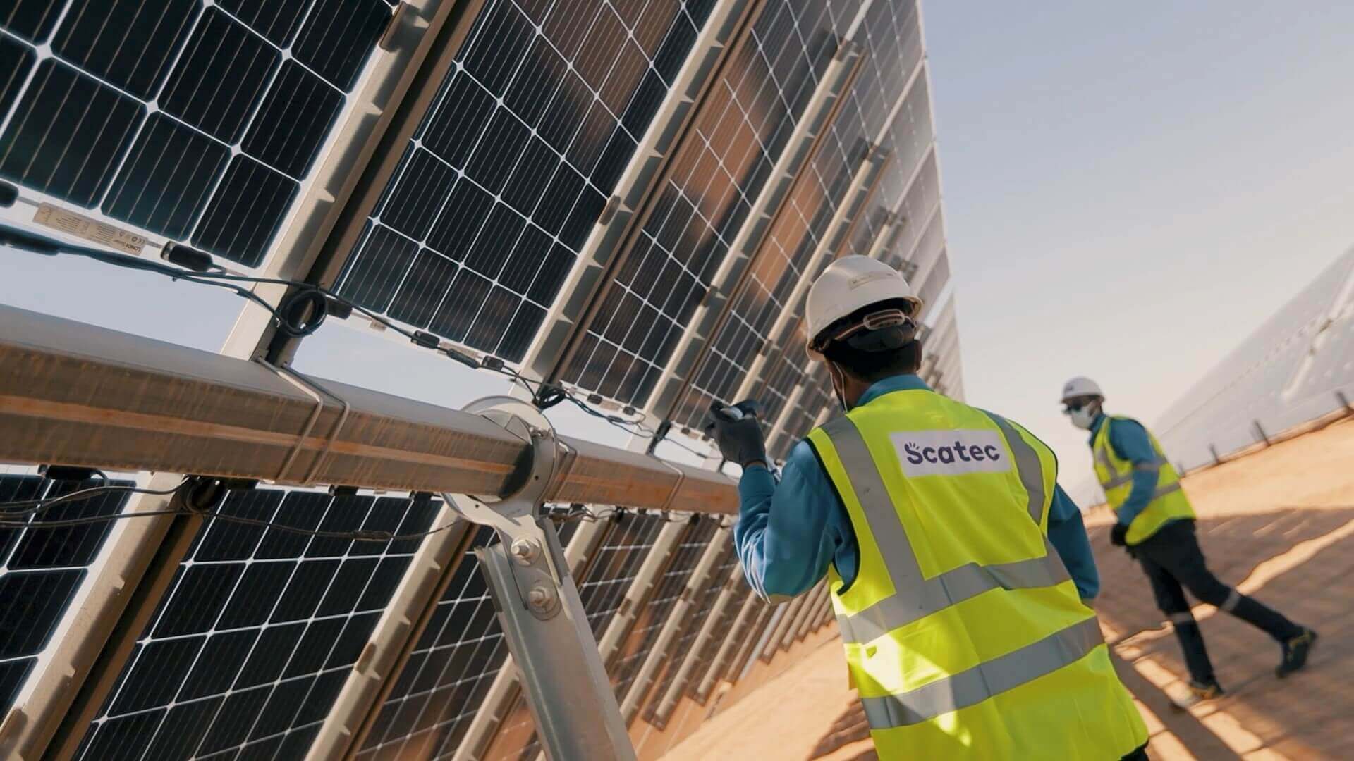 Two engineers underneath row of solar panels