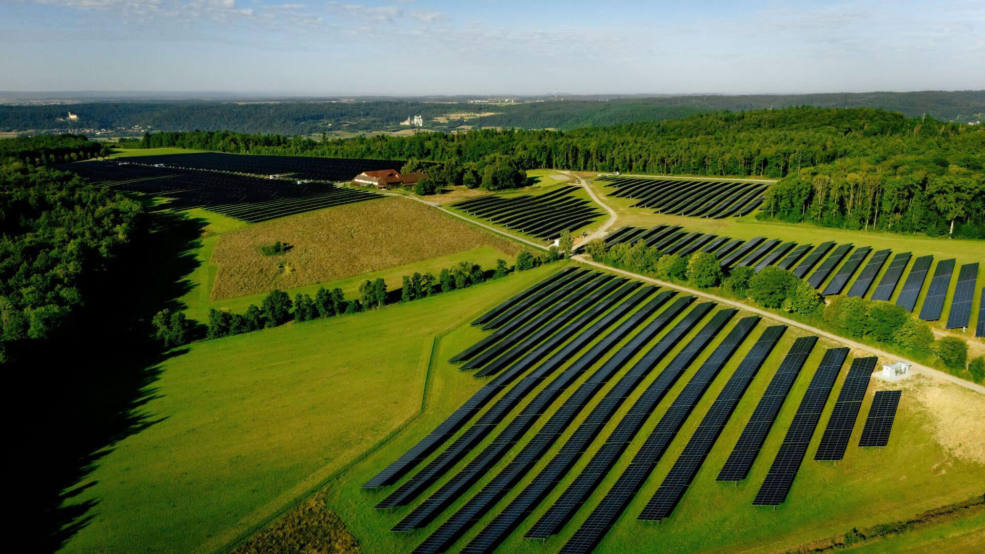 Aerial view of solar farm amongst green fields and trees