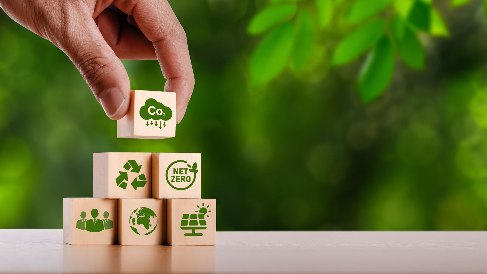 A hand stacking wooden blocks with icons