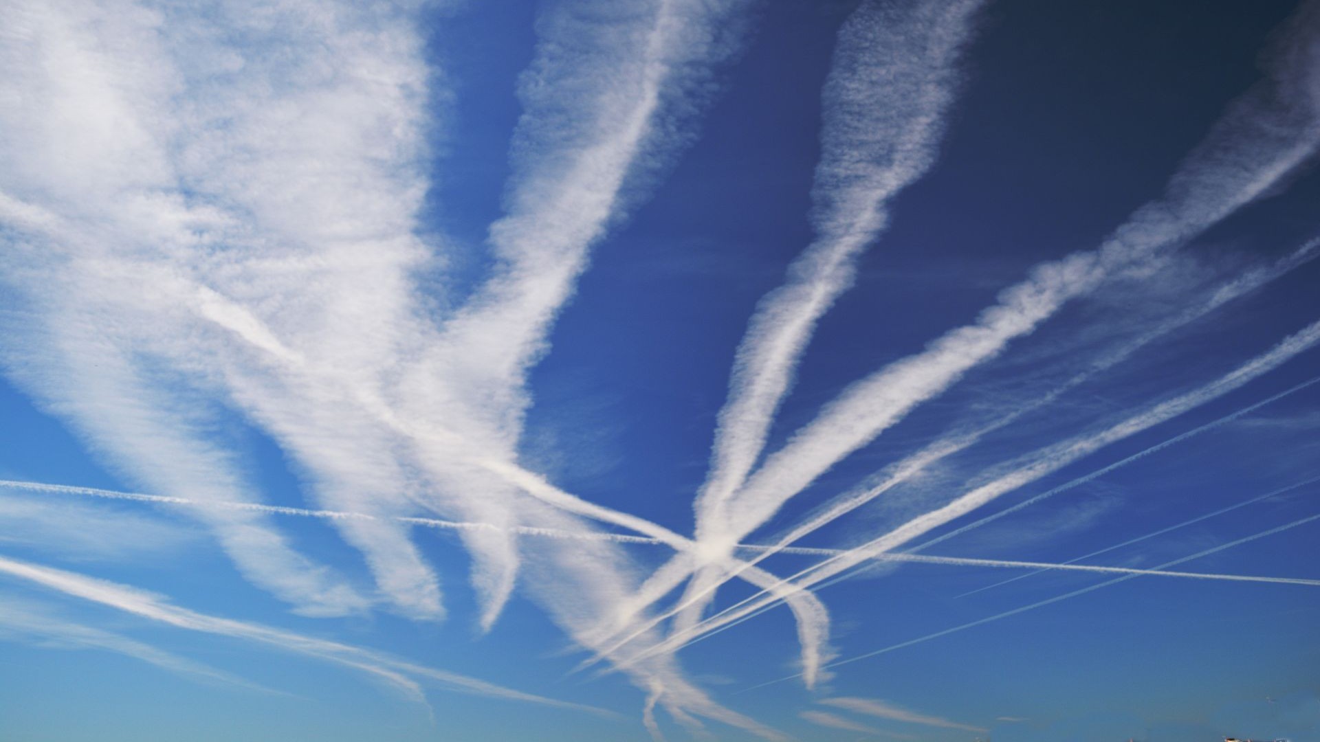 White contrails crisscrossing a bright blue sky