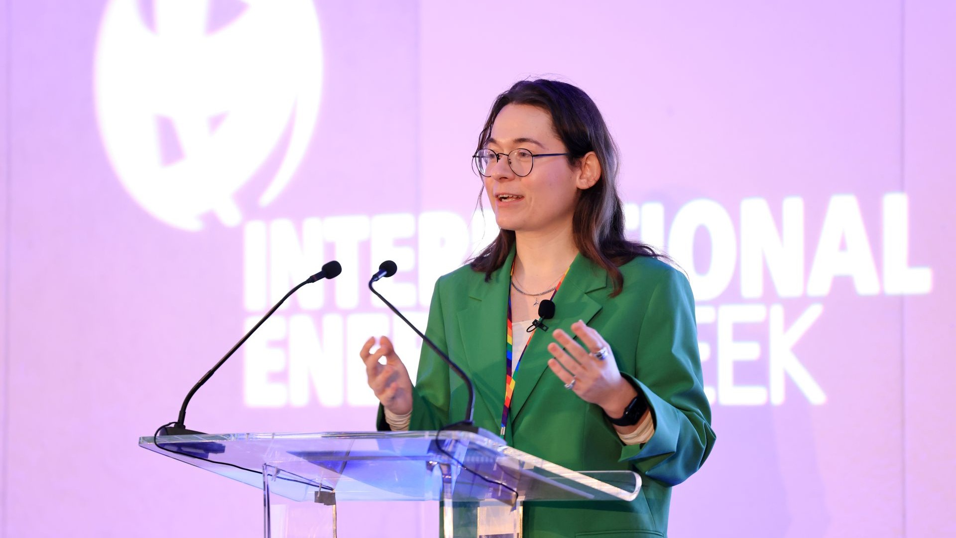 Woman standing behind lecturn, speaking to conference delegates, screen with Energy Institute logo and works International Energy Week behind her