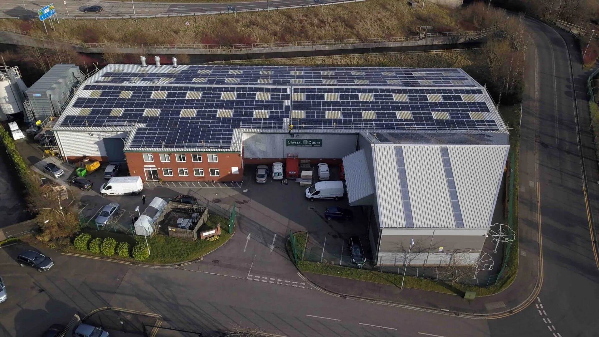 Aerial view over large industrial building with solar panels all over roof