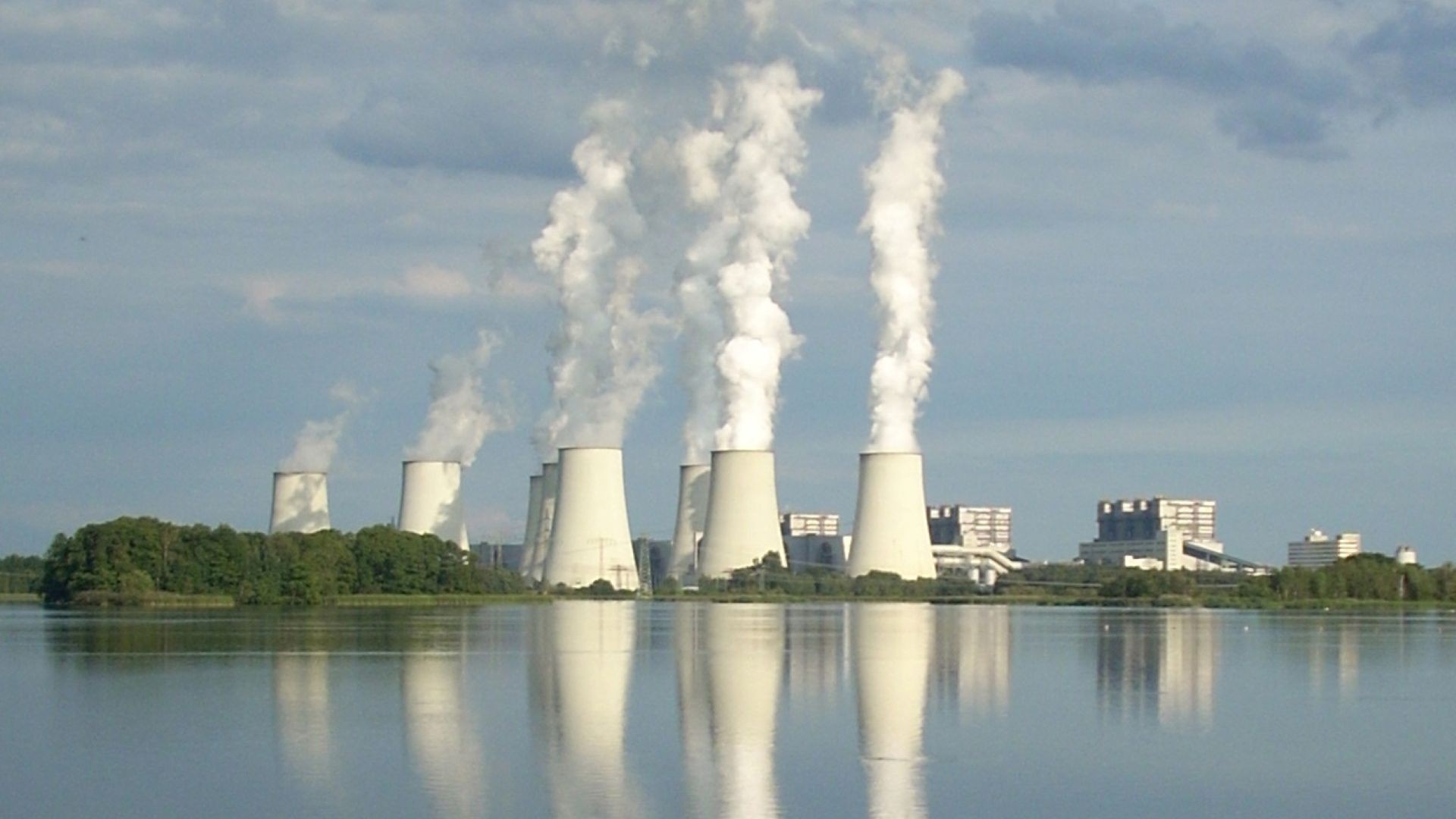 View of power plant with large clouds of smoke coming from chimneys