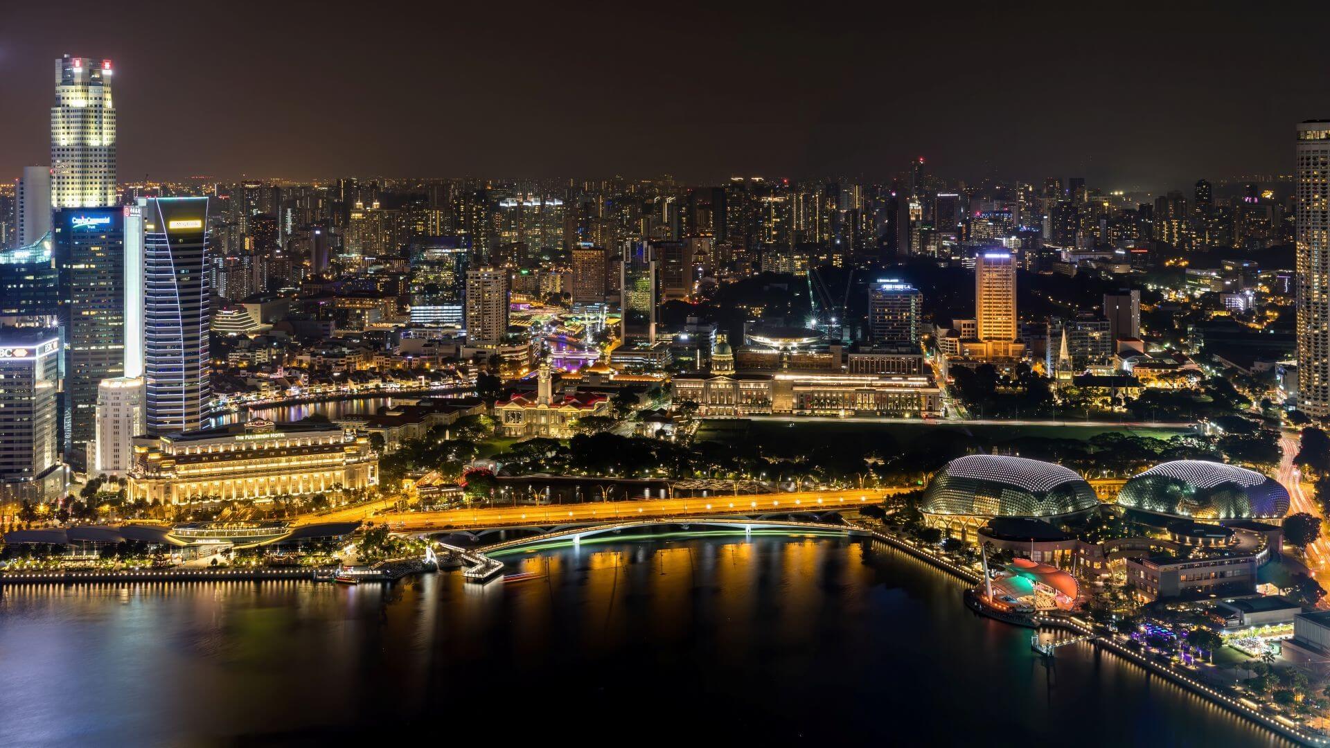 Aerial view over Singapore at night, showing city lights and shoreline