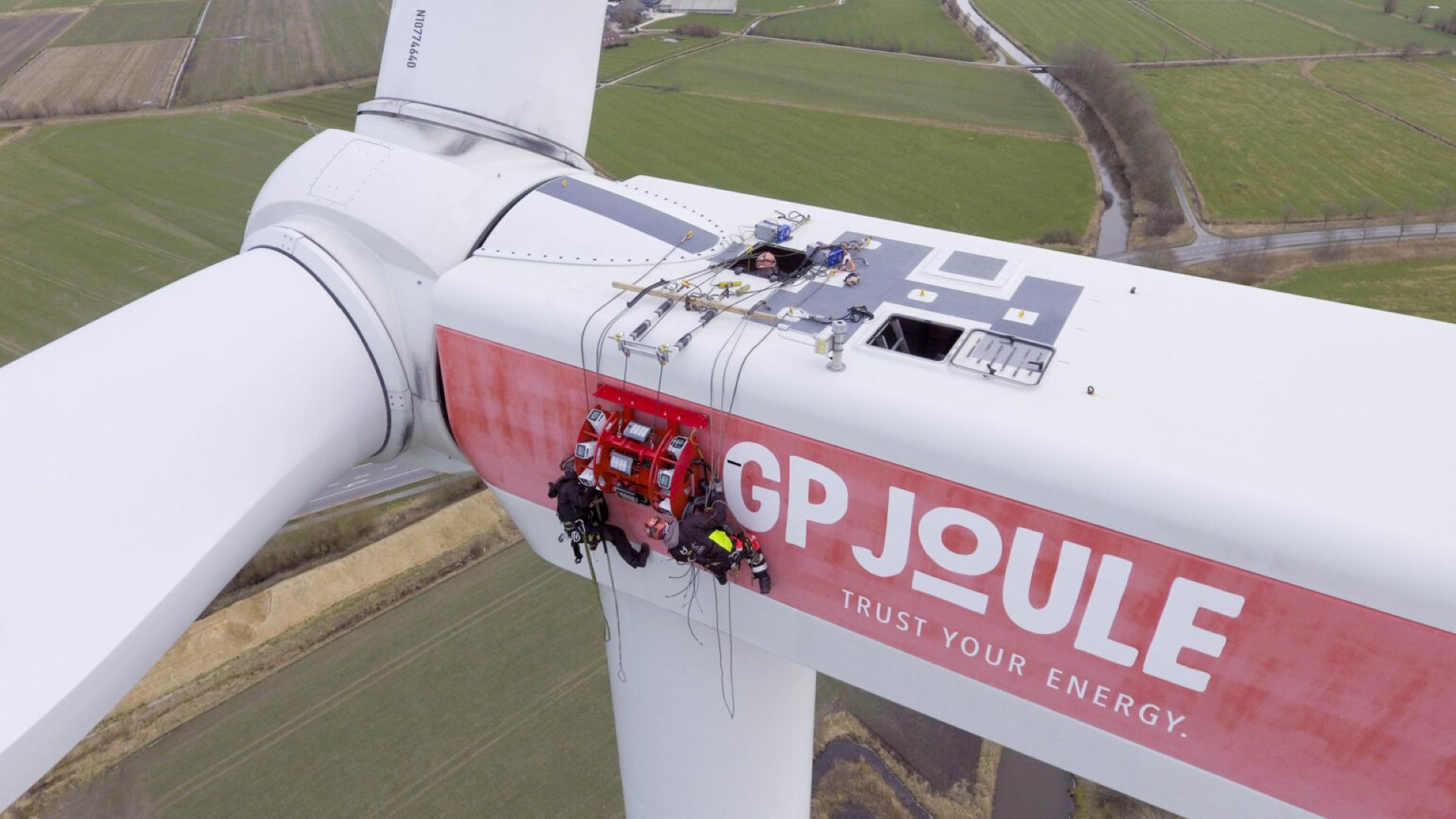 Two engineers harnessed on to side of wind turbine