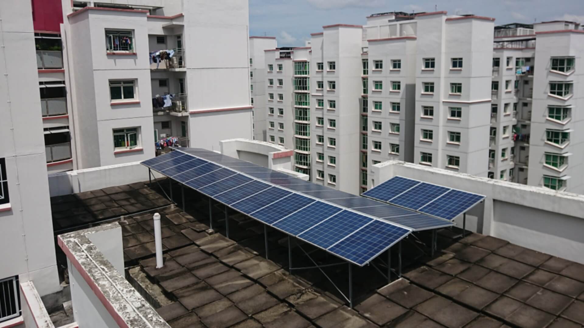 View of rooftop solar panels on top of a high-rise building, with other high-rise blocks in the background