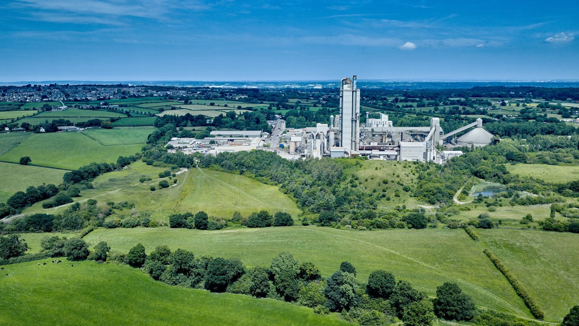Aerial view over industrial facility set among green fields and against a blue sky