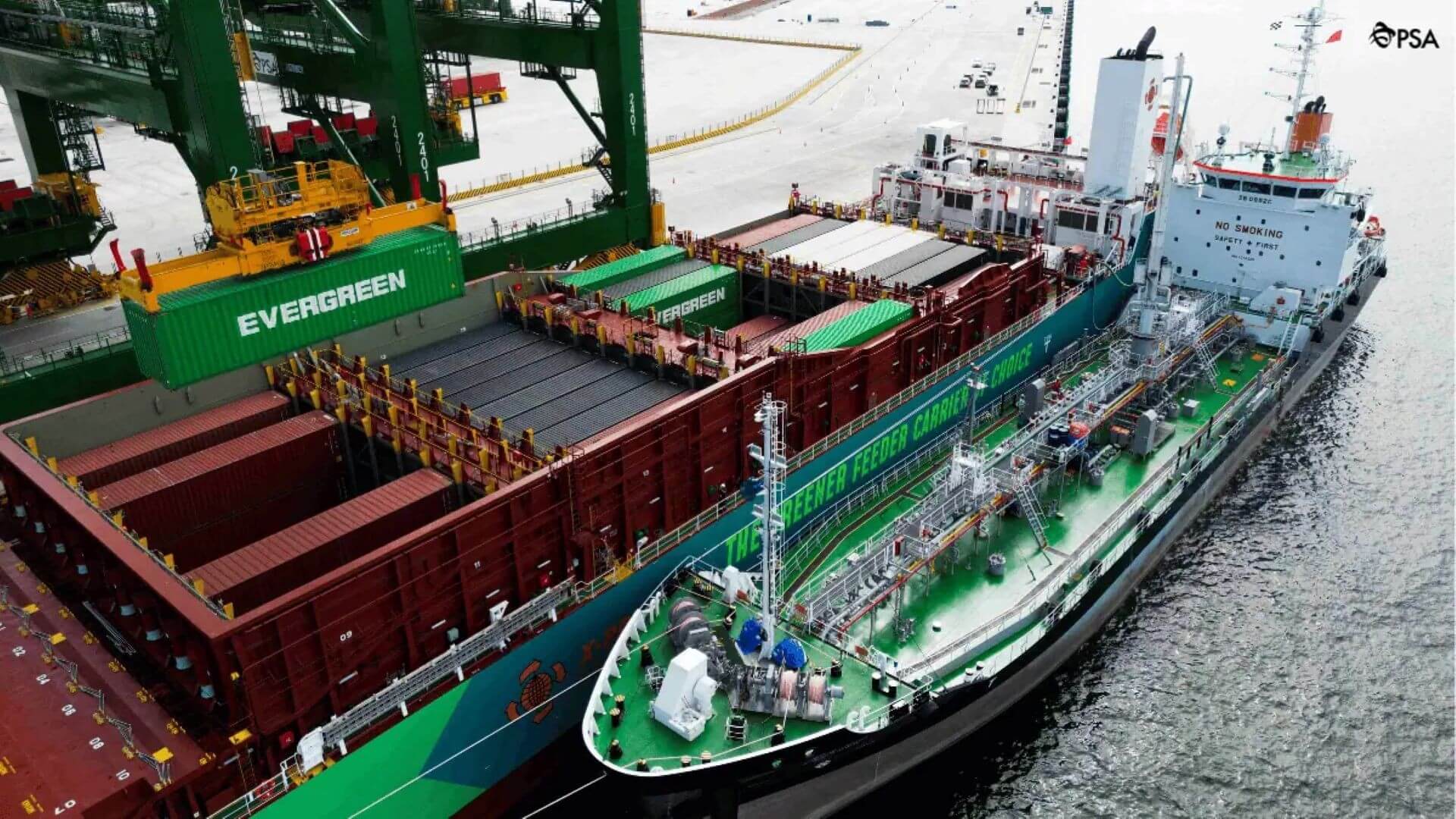 View of port terminal with large ship with large containers onboard, and bunker fuel vessel moored alongside,