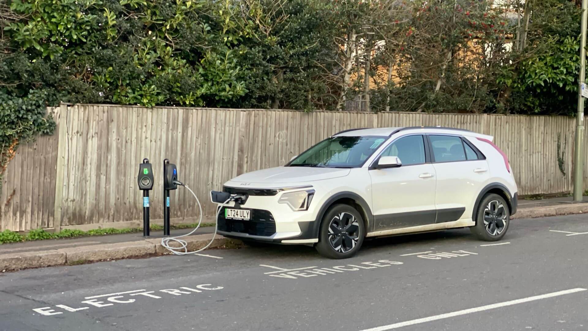 White electric car charging on side of road