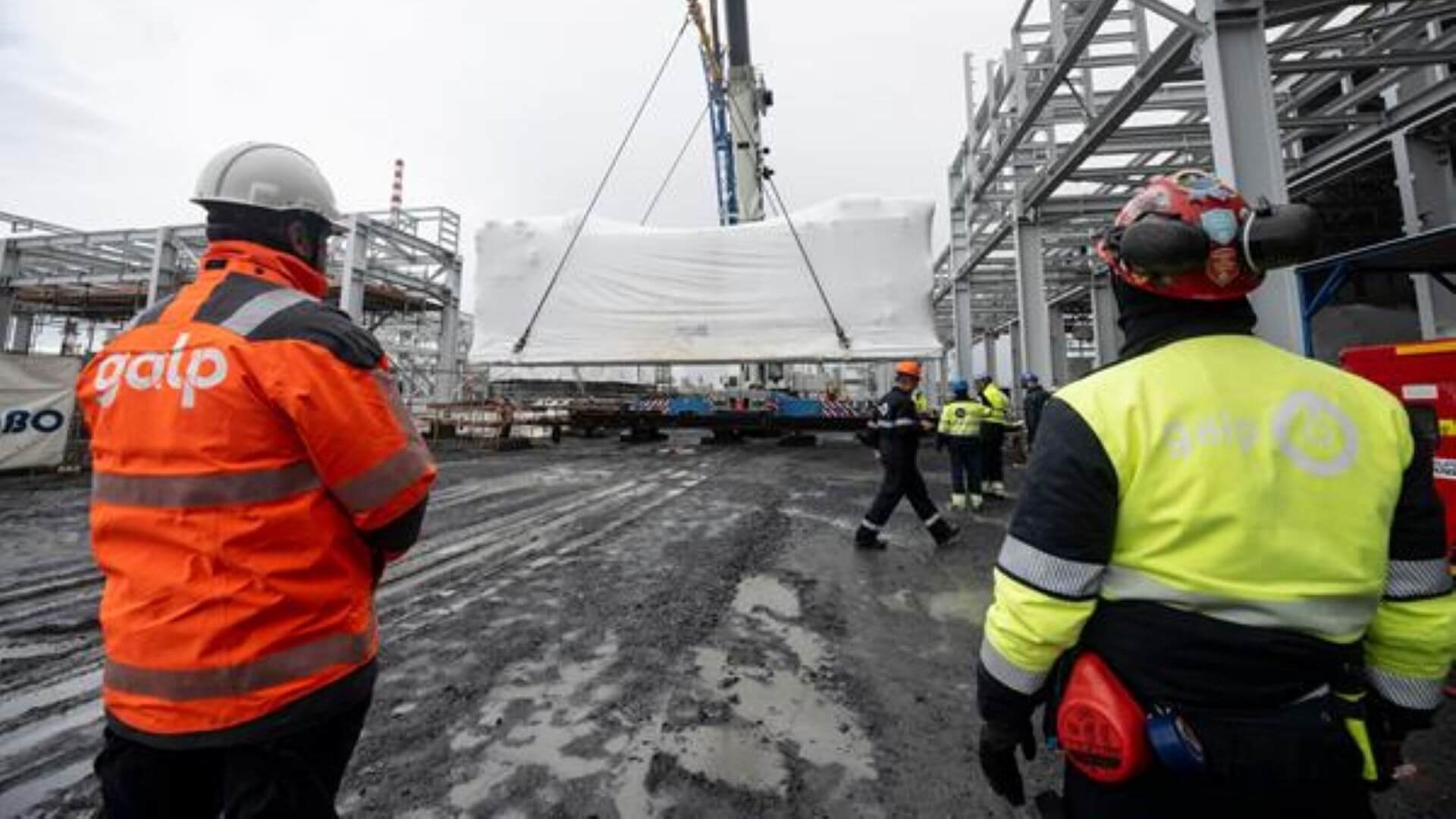Engineers in foreground watching installation of electrolyser unit