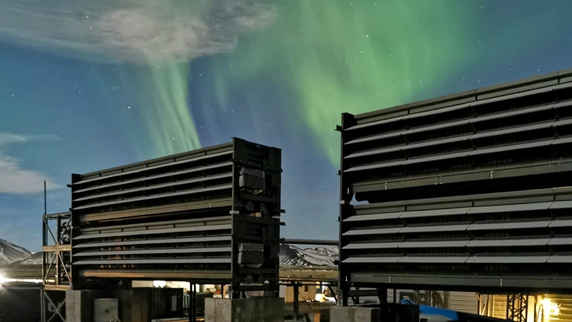 Outside of Orca plant with Northern Lights visible in sky behind