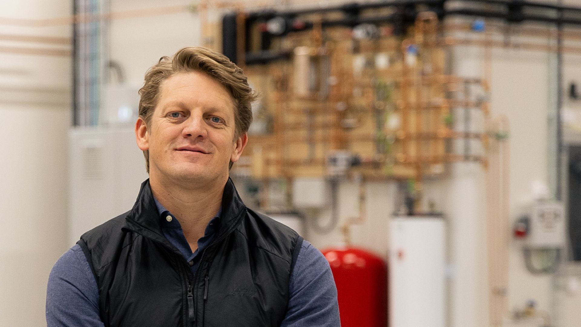 Head and shoulders photo of Kaj af Kleen nstanding in front of blurred background of plant pipework and control panel