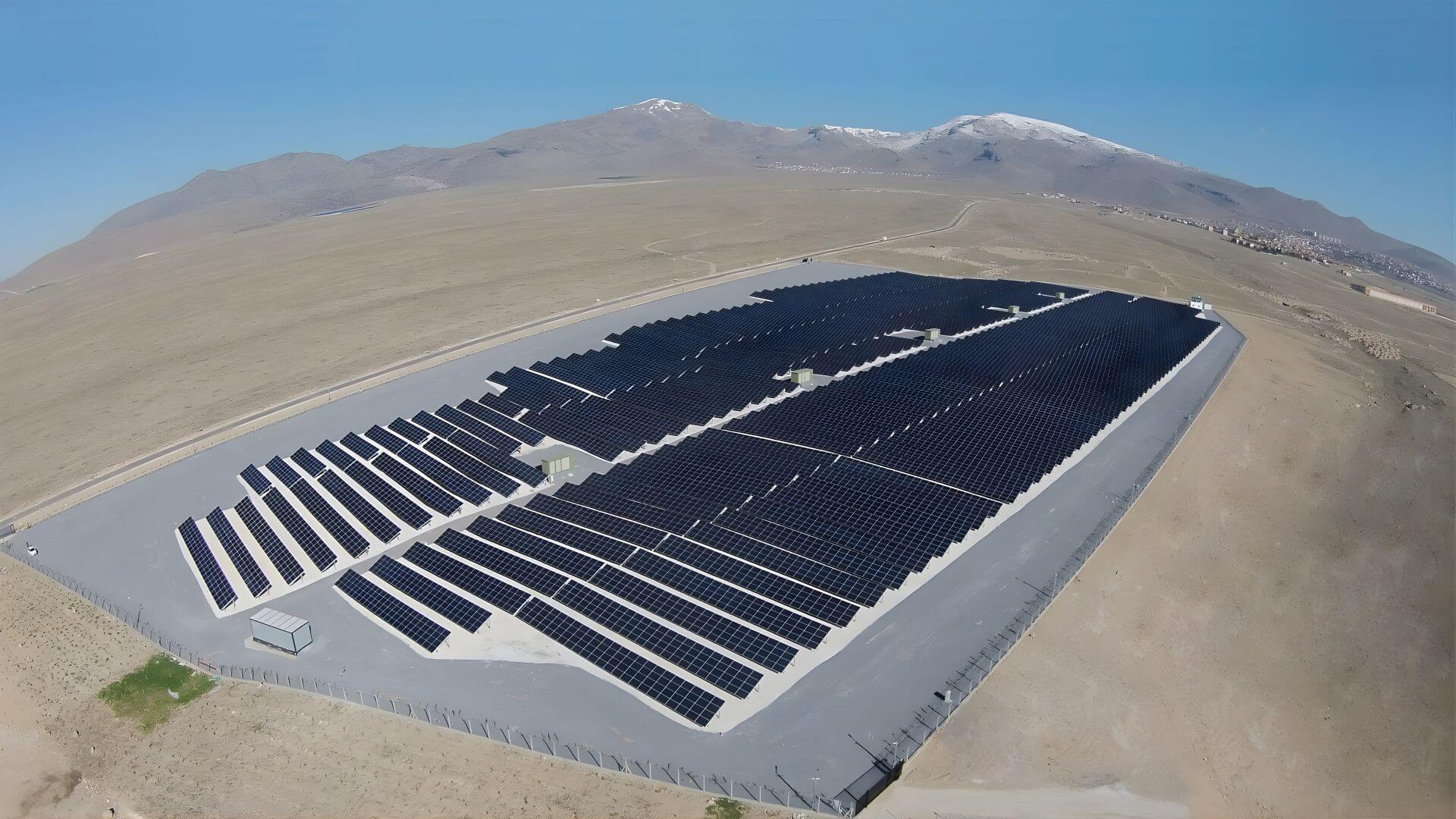 Aerial view of solar farm in desert with mountains in background