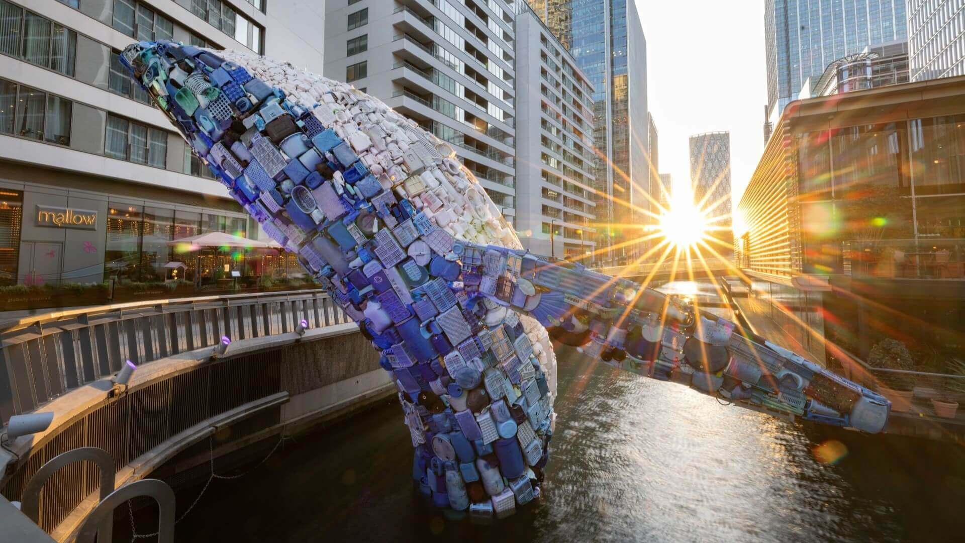 Sculpture of a whale's tail over water in built up area