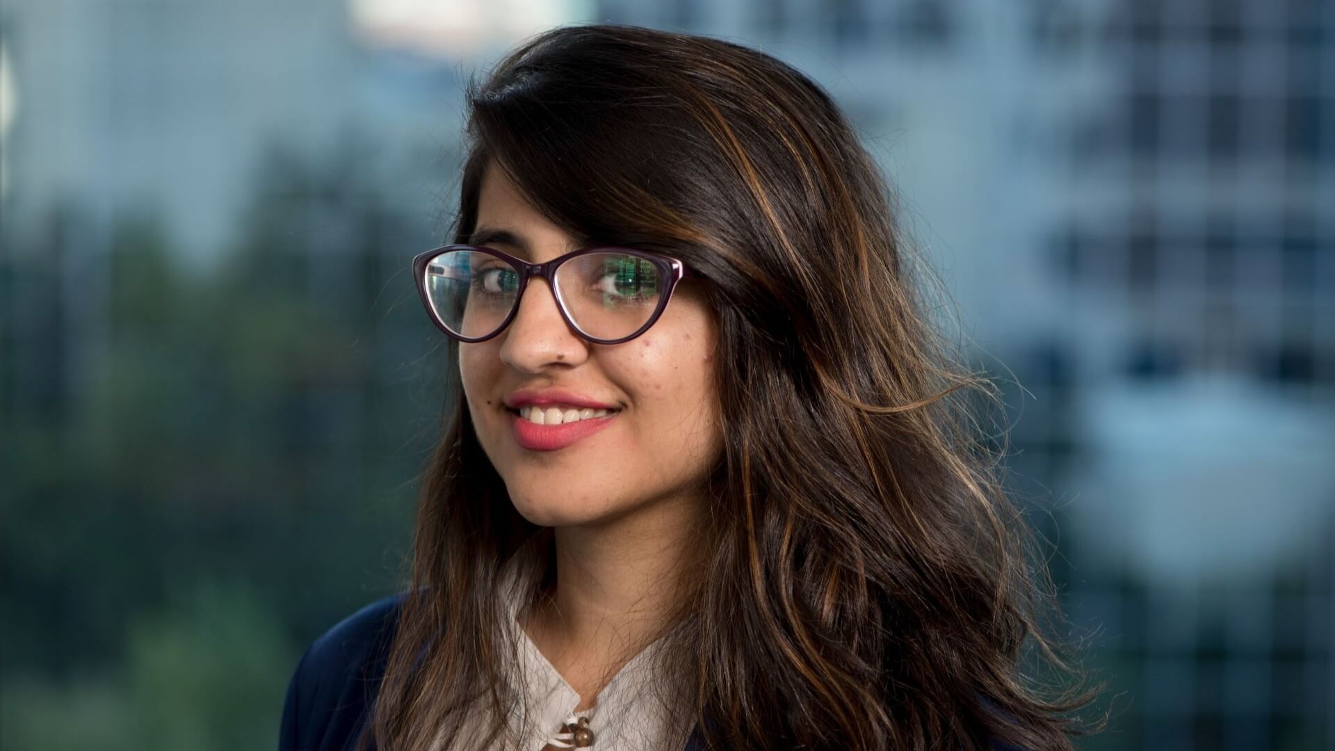 Head and shoulders photo of Deepa Pahuja, standing outside with blurred out building and vegetation in the background