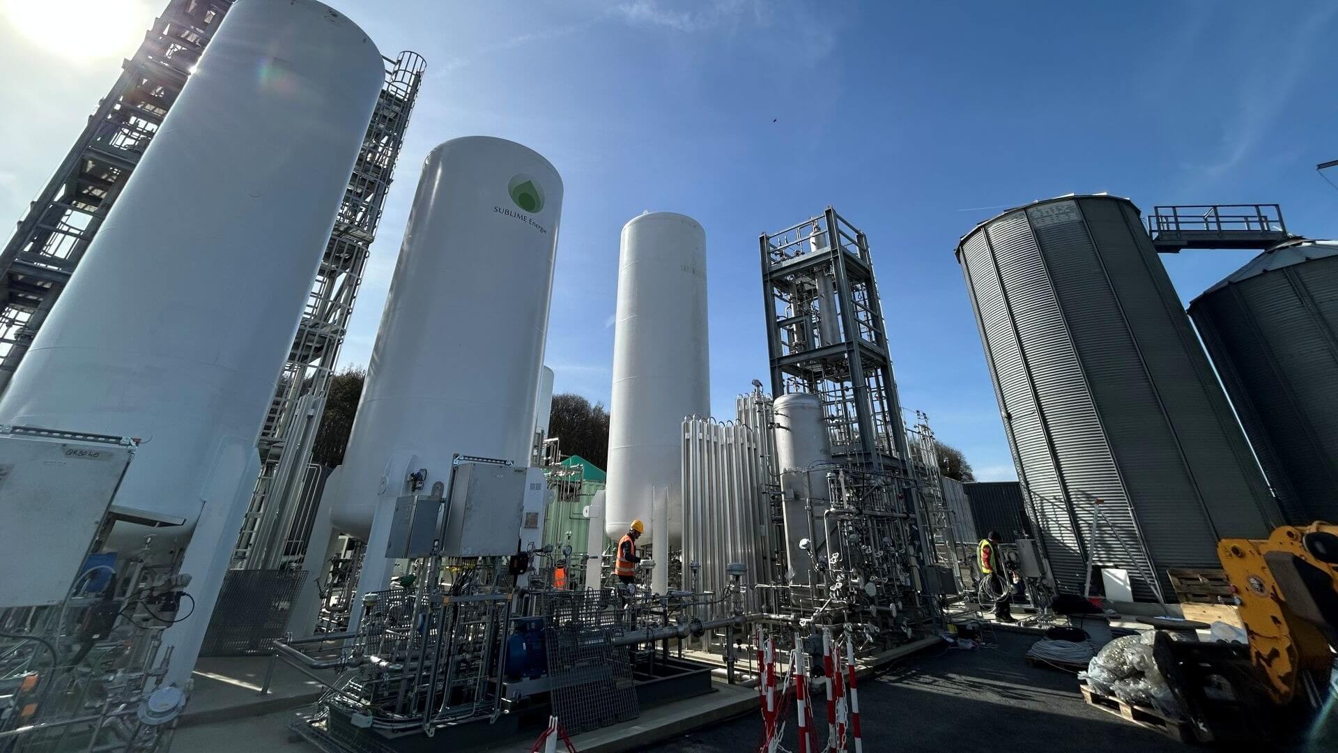Industrial plant comprising tall cylindrical towers and pipework set against blue sky