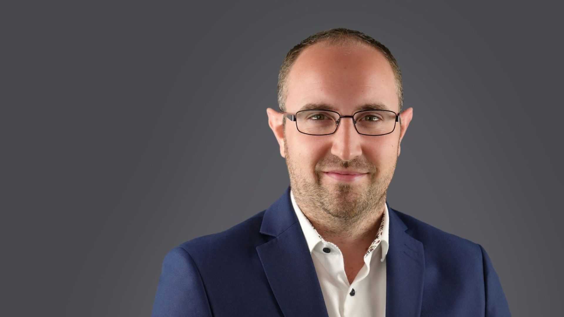 Head and shoulders photo of Jonathan Lewin, set against a dark grey background