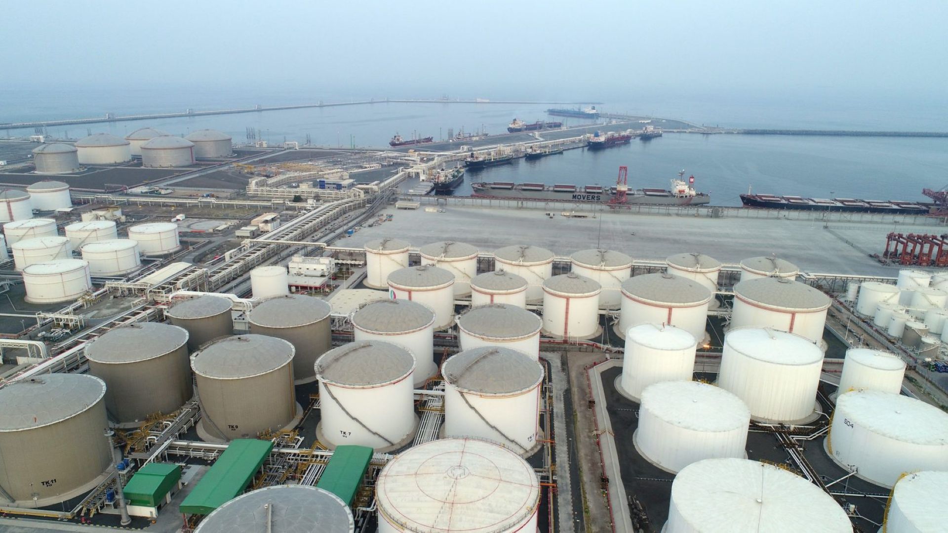 Aerial view over Fujairah oil tanker terminal, showing row upon row of storage tanks, with tankers berthed at jetties in the distance
