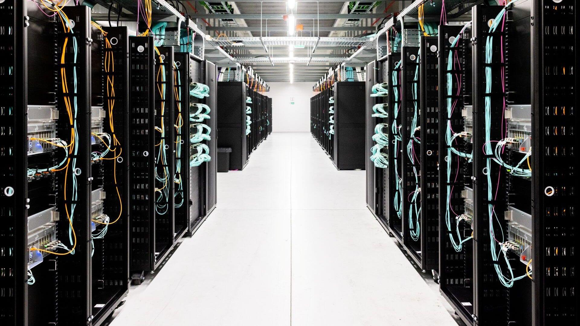 Looking down a between a row of two long banks of large mainframe computer units