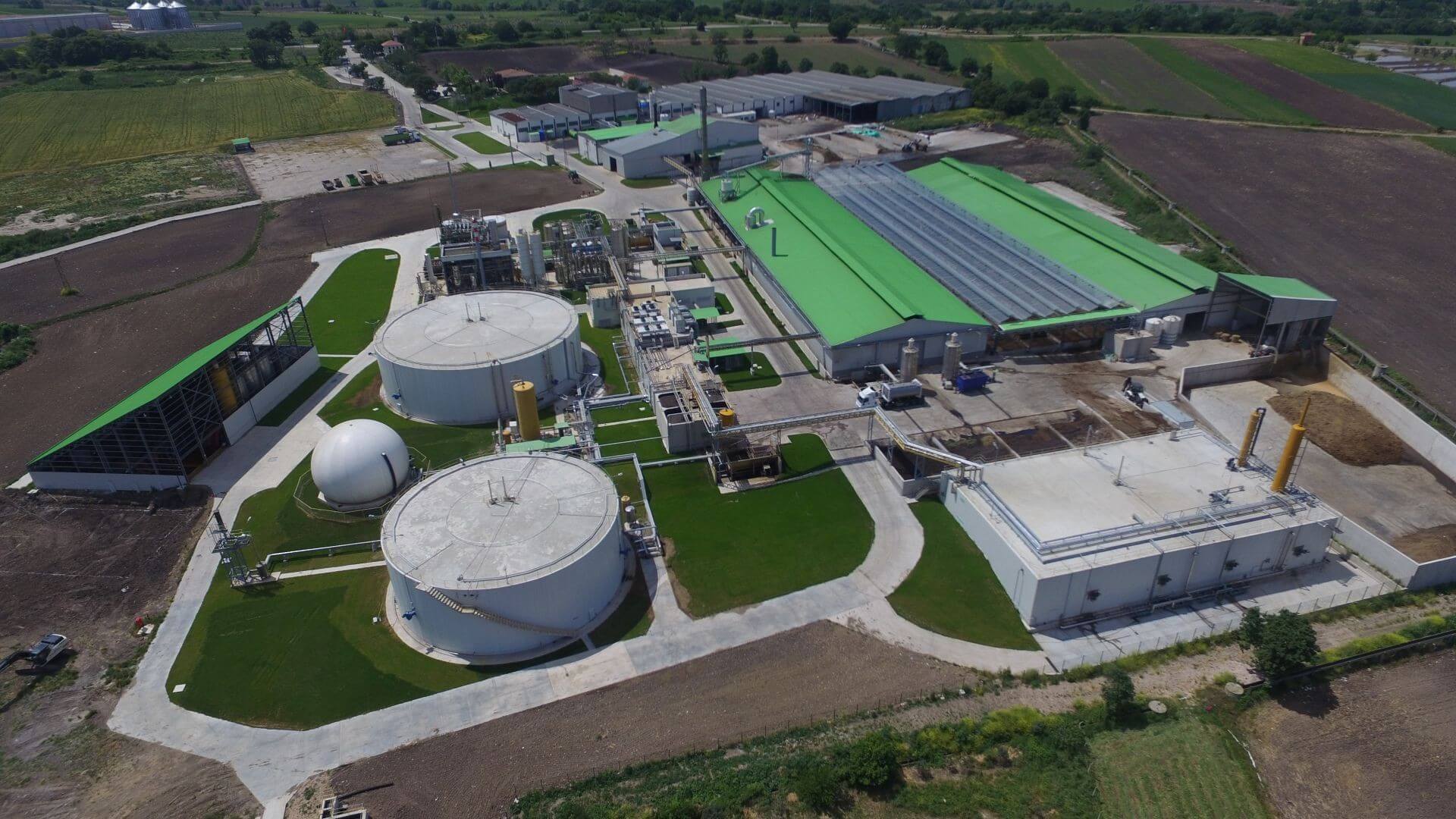 Aerial view over an industrial plant, showing cylindrical storage tanks, pipework and rectangular buildings