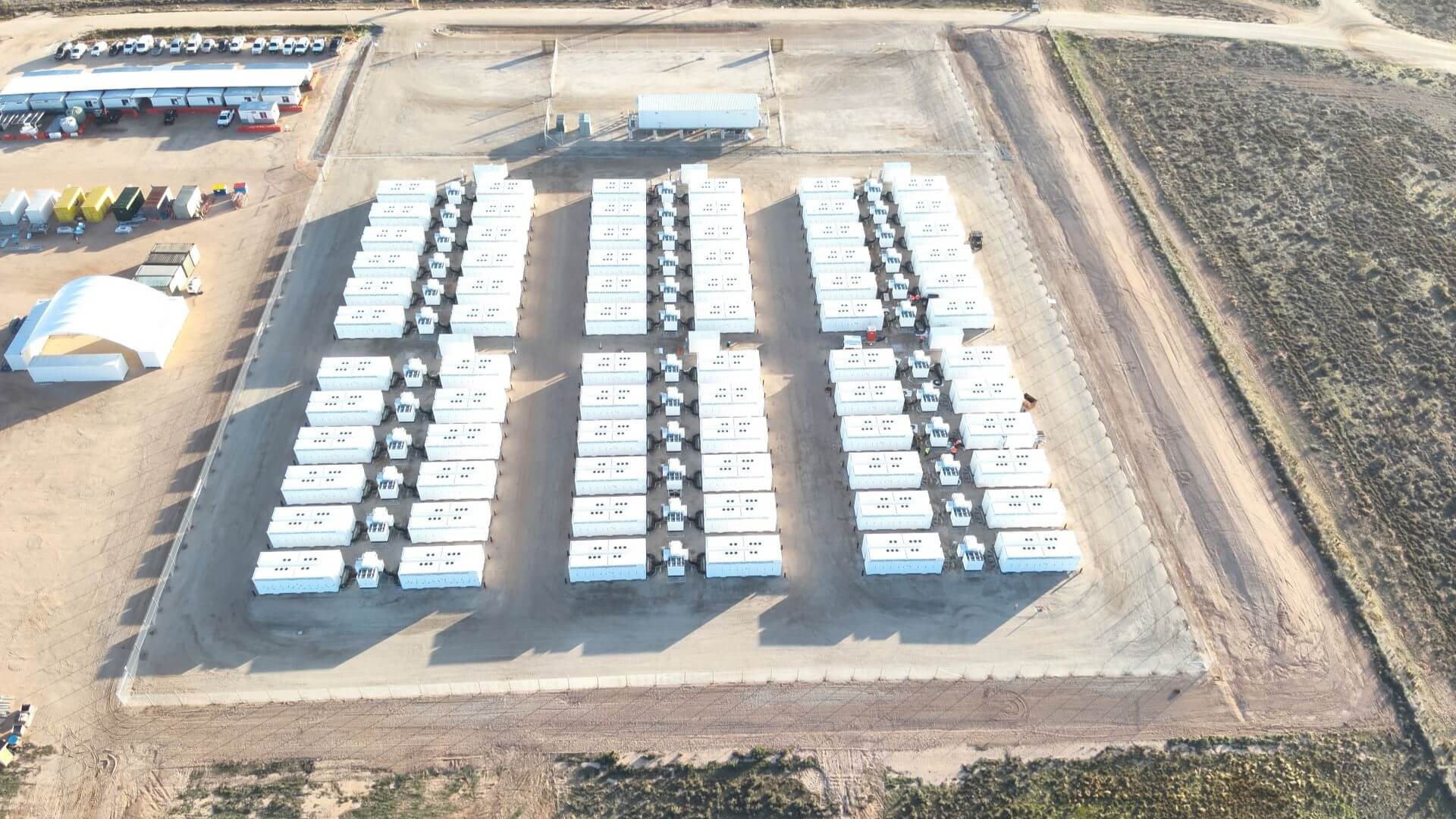 Aerial view over rows of rectangular battery energy storage systems set out in a square grid