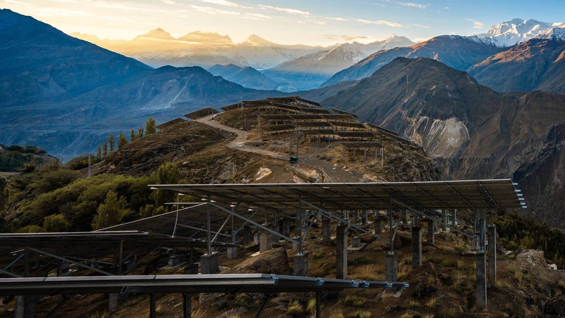 Close view of solar panel, with other extending on hillside in to distance, with mountains beyond