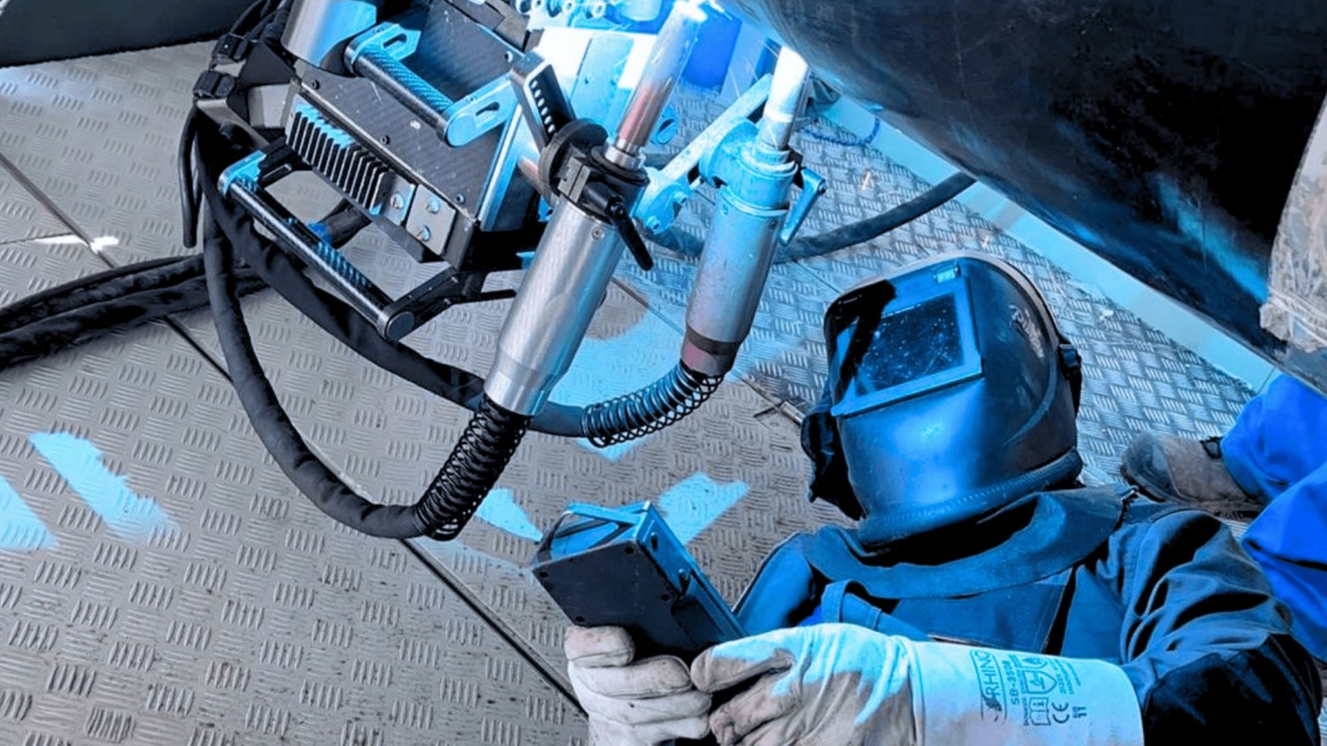 Welder in protective wear inspecting pipeline